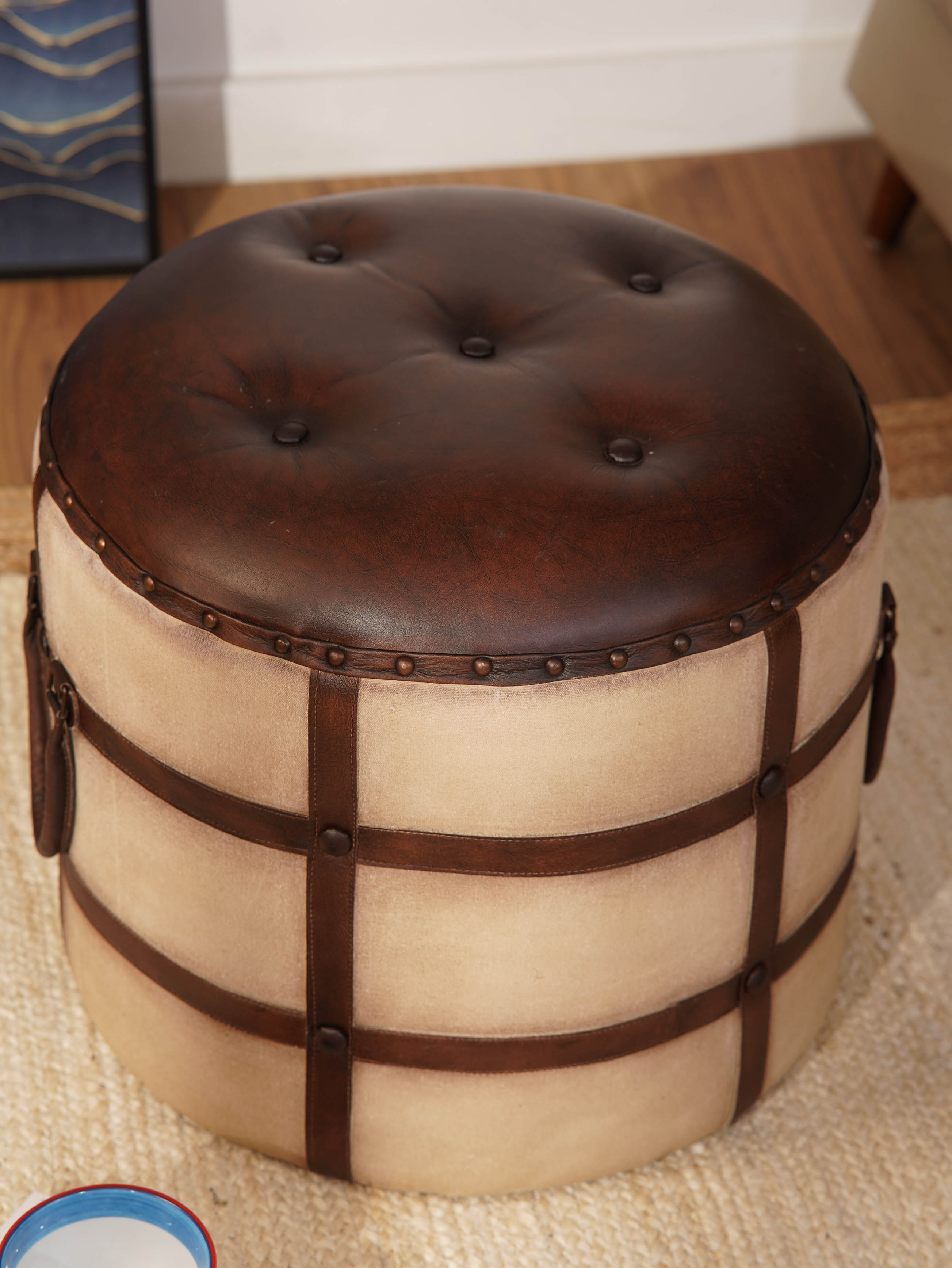 Top-down view of circular ottoman with dark brown tufted leather seat
