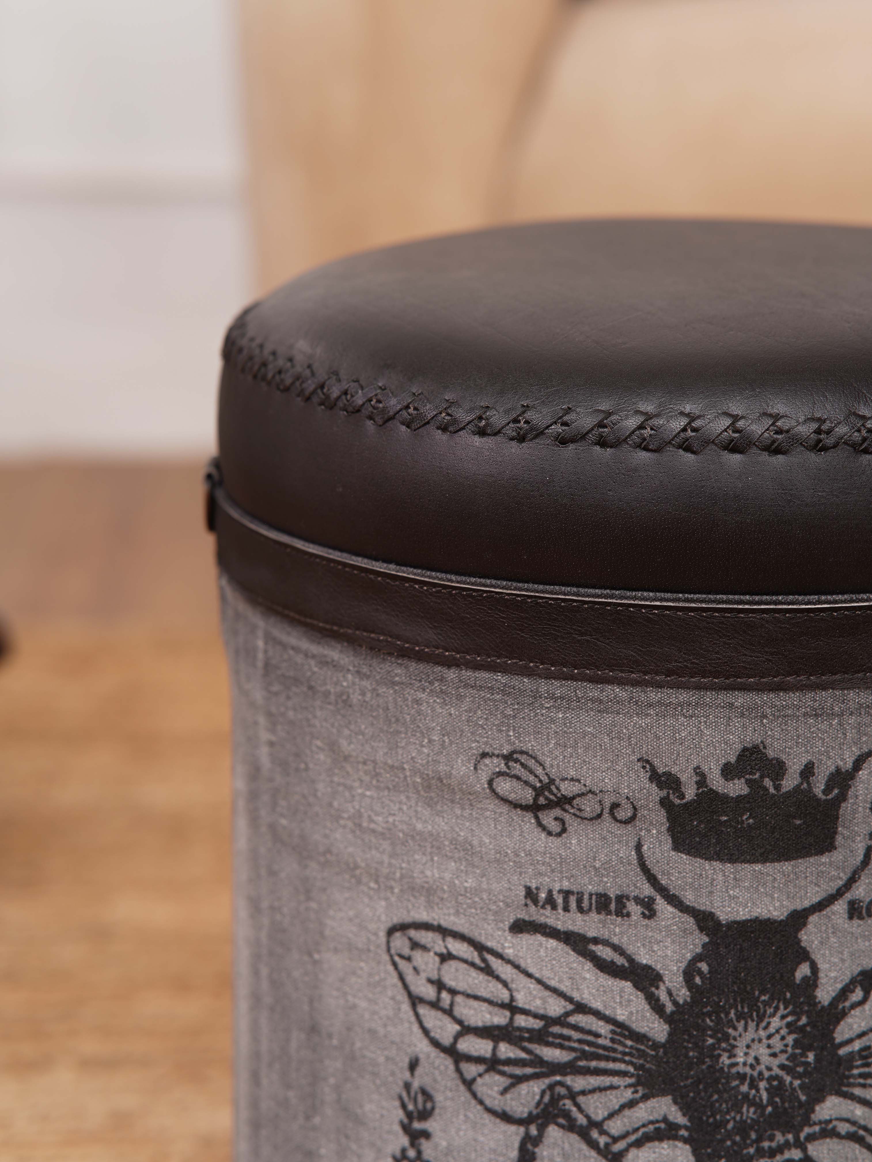 Cylindrical ottoman showing canvas panels and leather-wrapped top