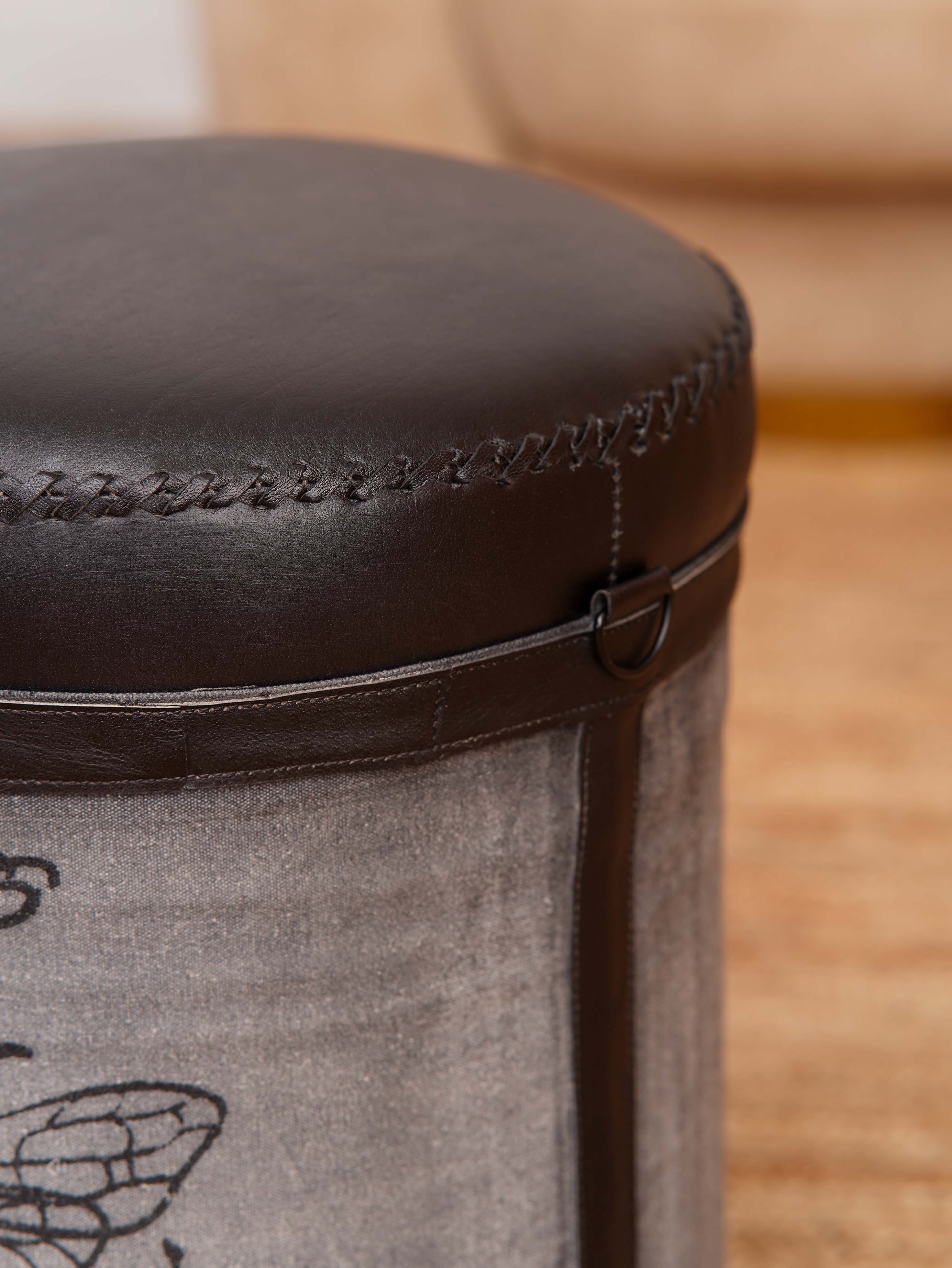 Cylindrical ottoman showing canvas panels and leather-wrapped top