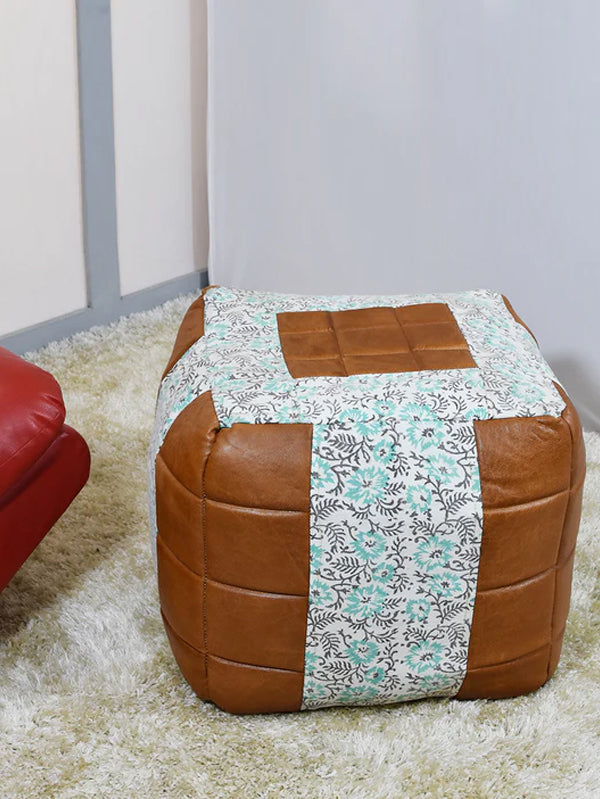 Square canvas and leather pouf beside chair and side table