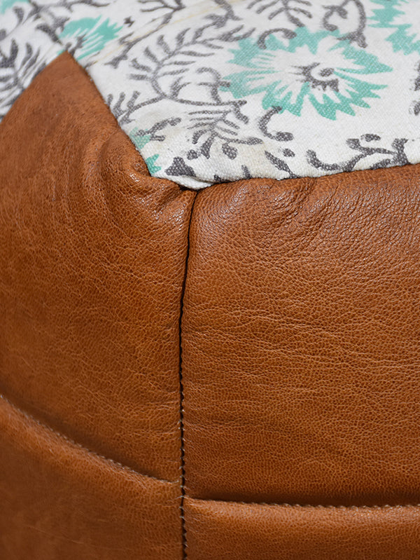Close-up of stitched brown-green pouf on wood floor