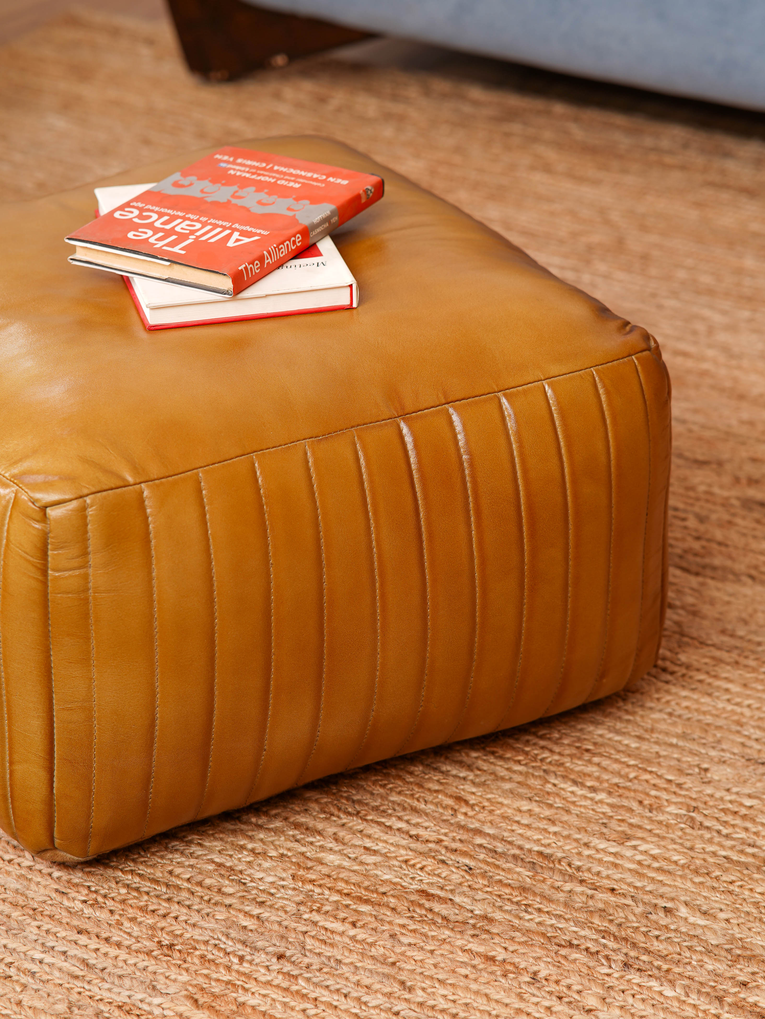 Top-down view showing stitched pattern on beige square pouf