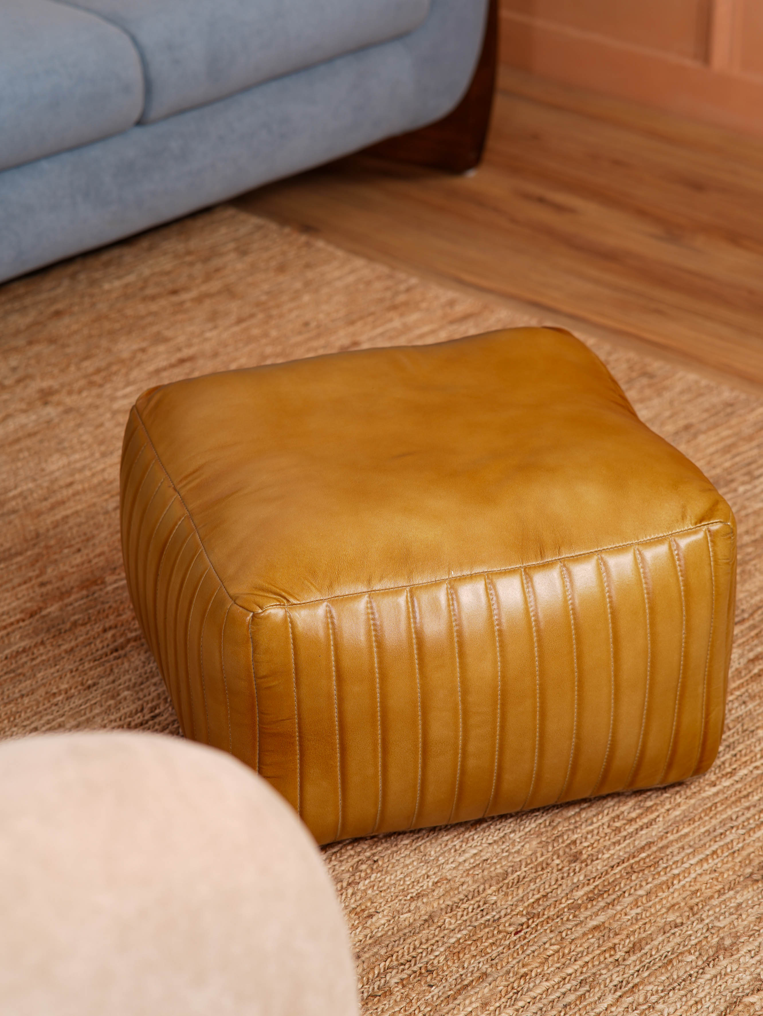 Top-down view showing stitched pattern on beige square pouf
