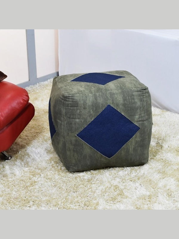 Olive green square canvas pouf with blue diamond design in a cozy living room setup