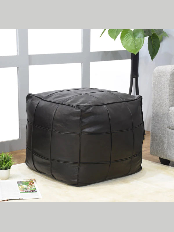 Black square leather pouf next to armchair in modern living room