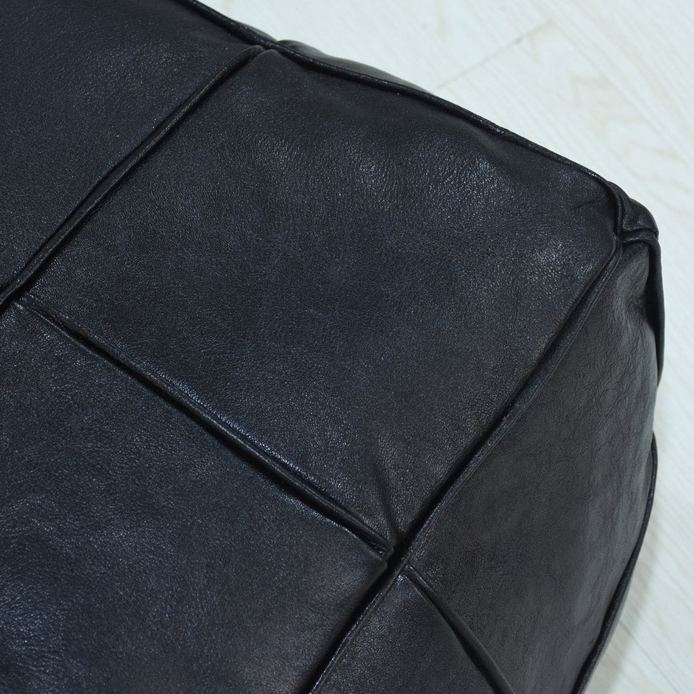 Detail of full grain leather and artisan stitching on black pouf