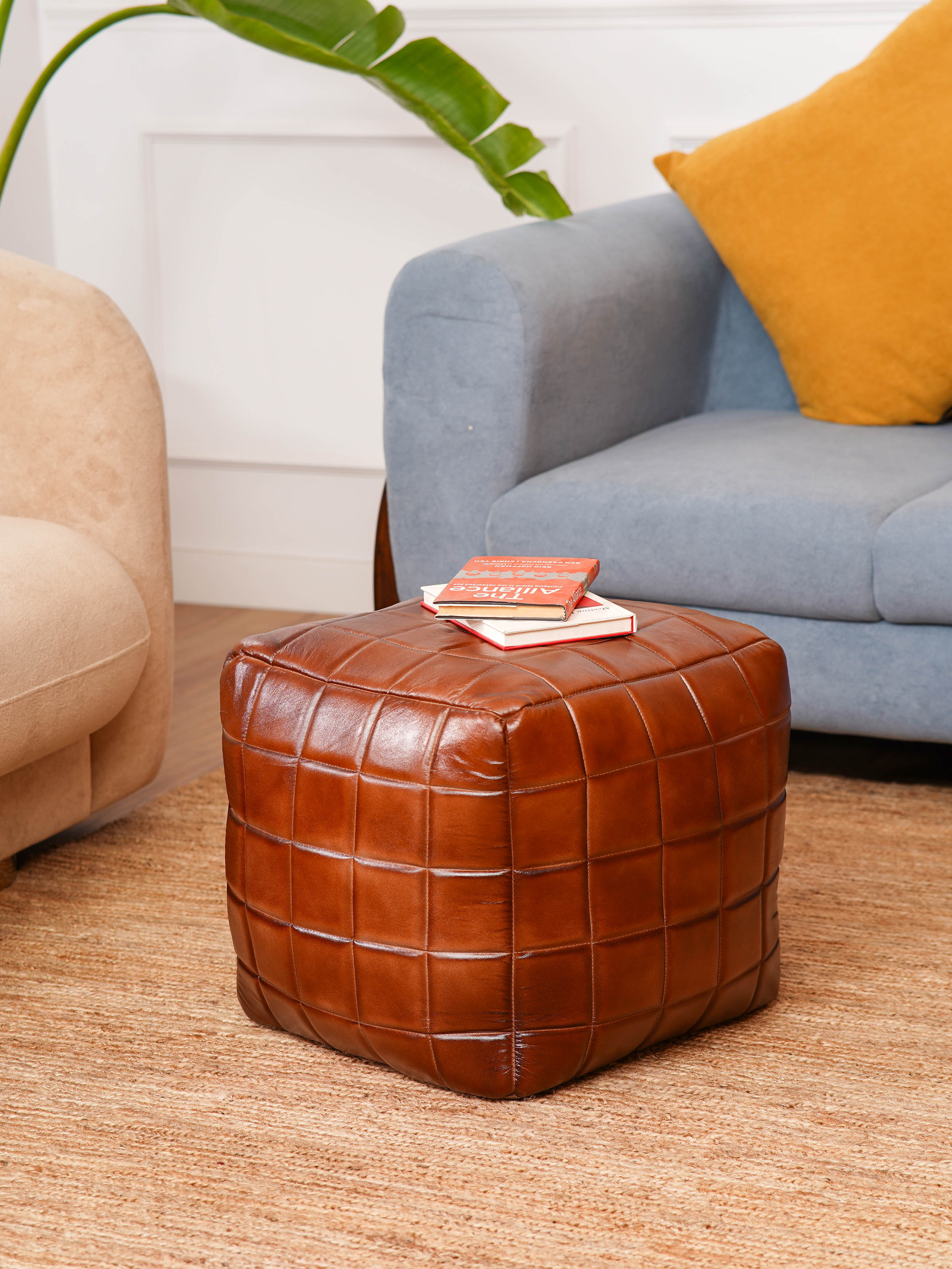 Brown leather square pouf beside modern blue armchair
