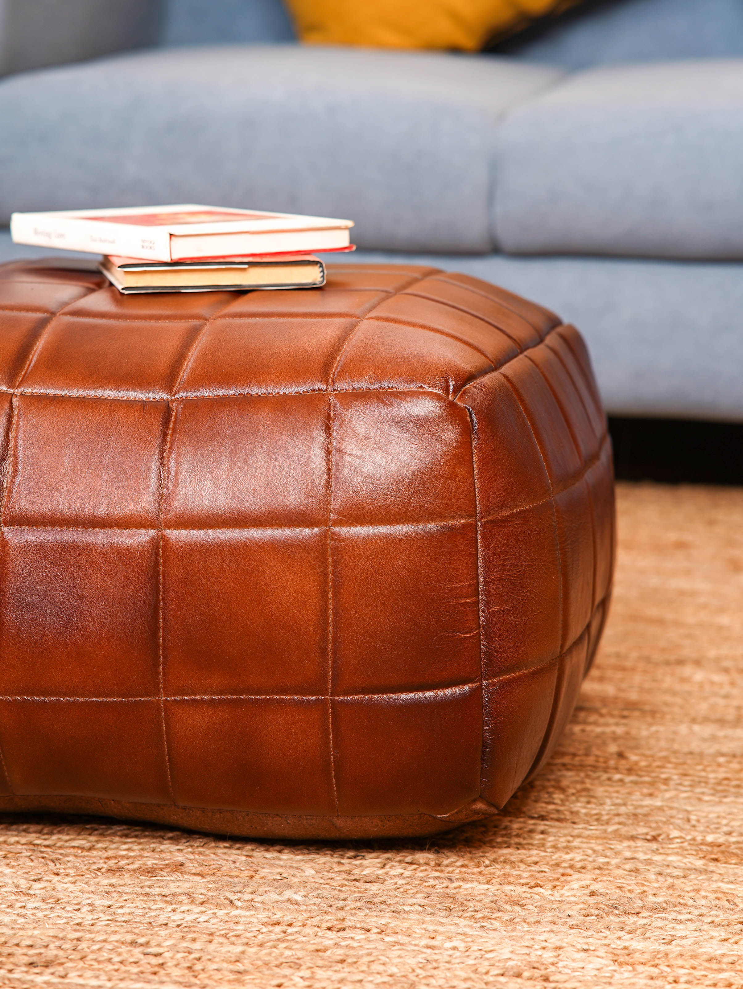 Hand-stitched grid pattern on brown square pouf