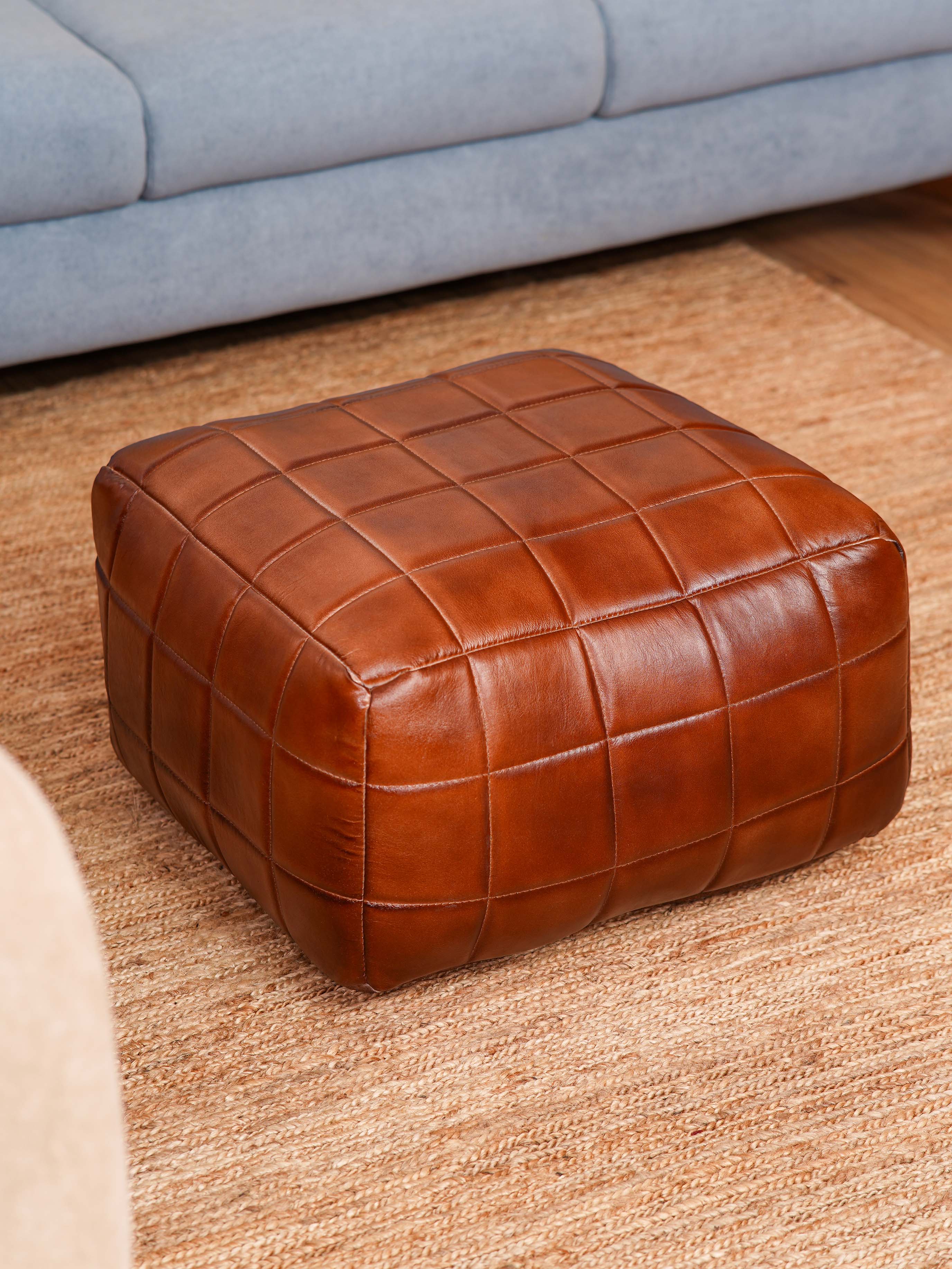 Hand-stitched grid pattern on brown square pouf