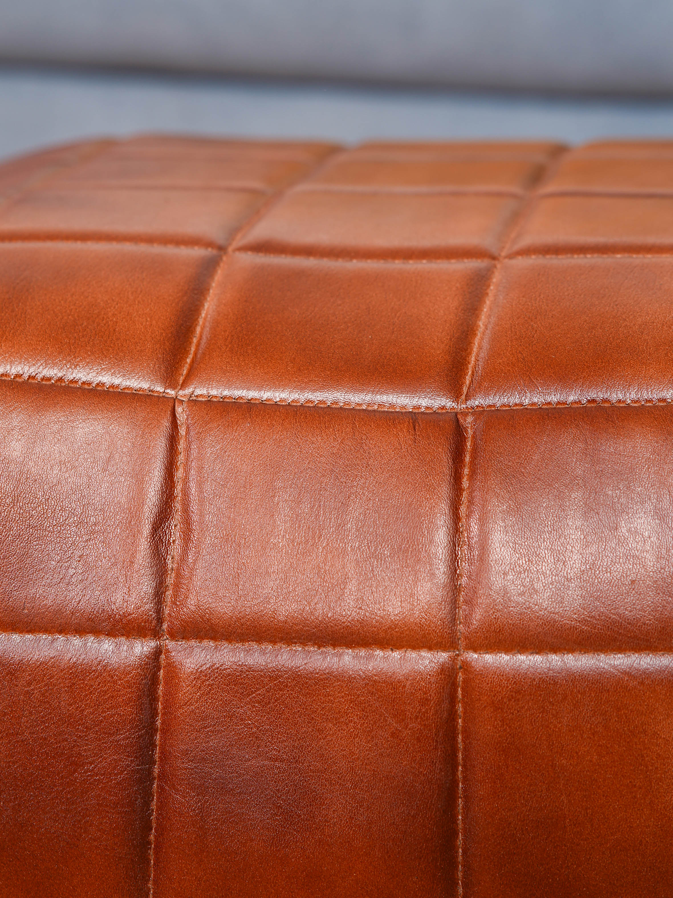 Hand-stitched grid pattern on brown square pouf