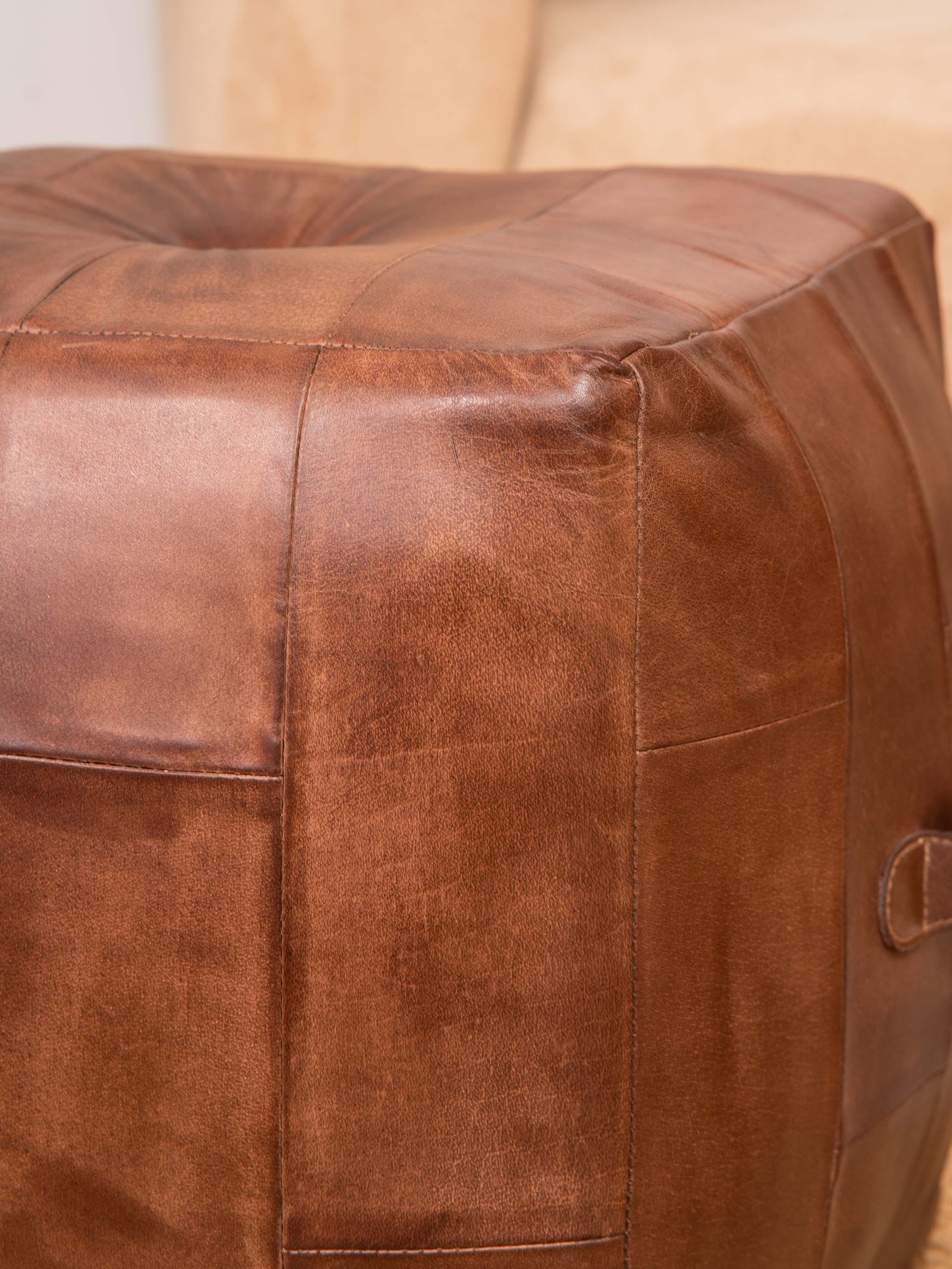Detail of stitching and leather texture on cognac buffalo pouf