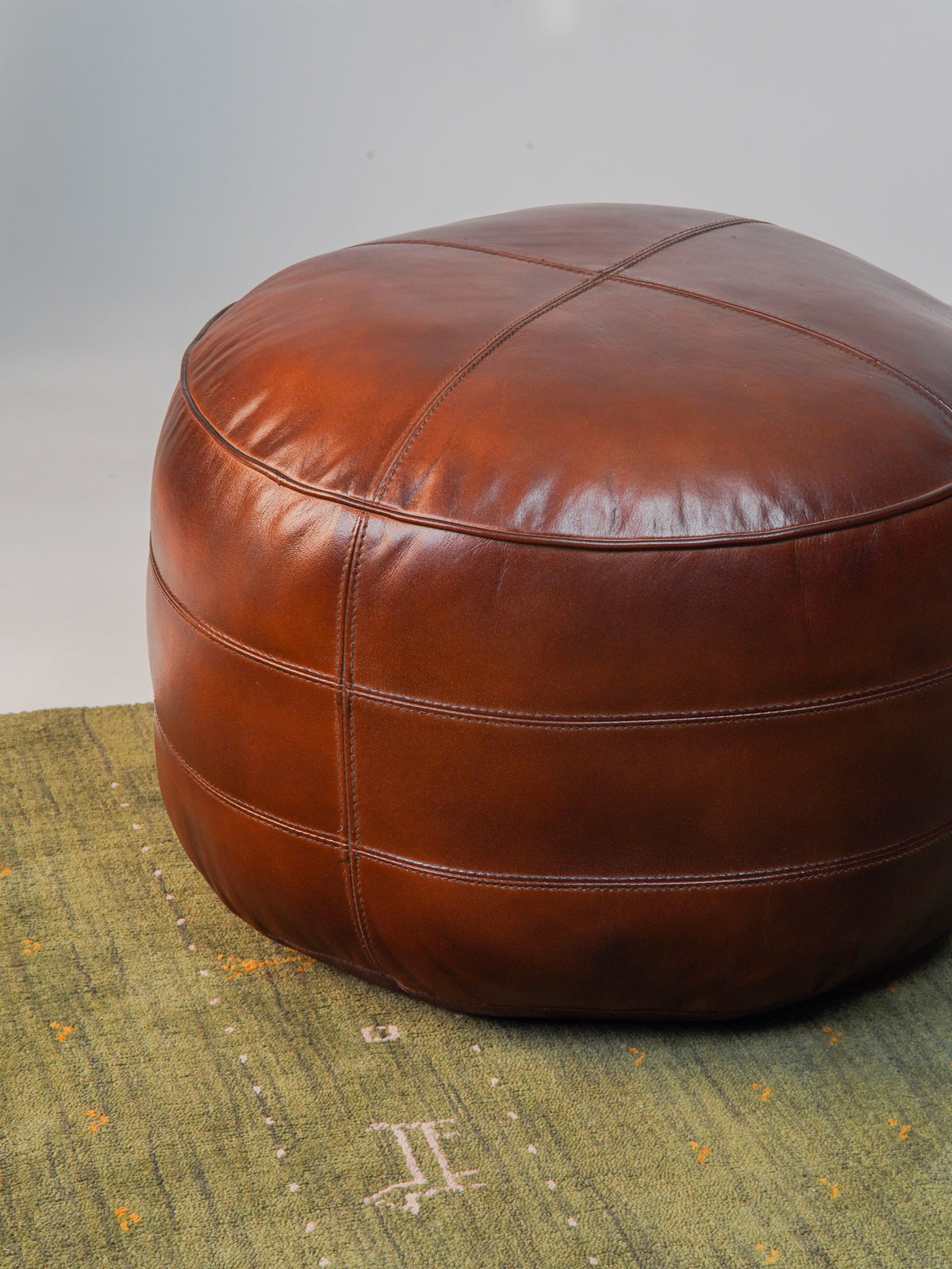 Top-down view of artisan-crafted leather pouf with center stitching