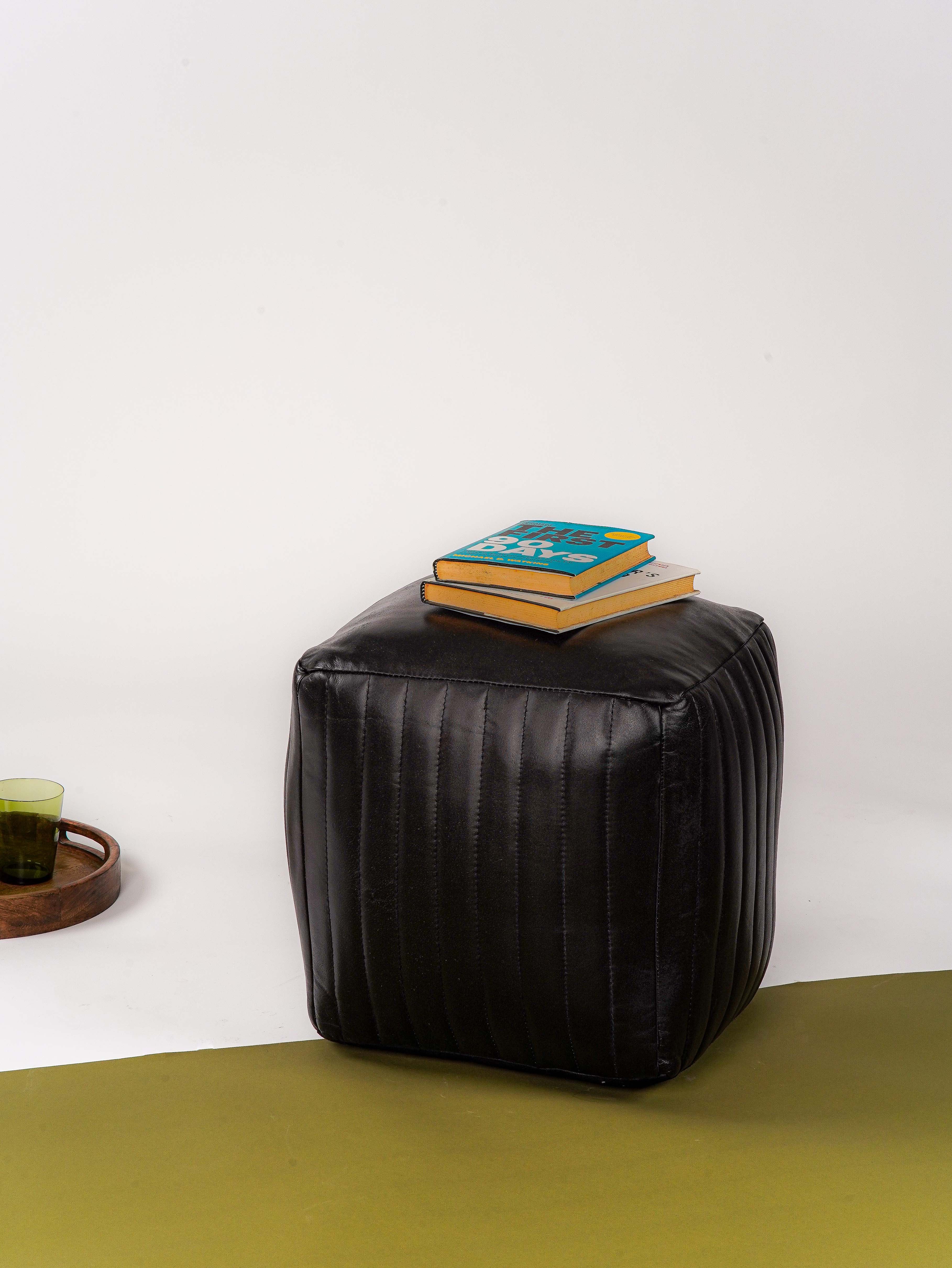 Square black buffalo leather pouf styled as table with books on top