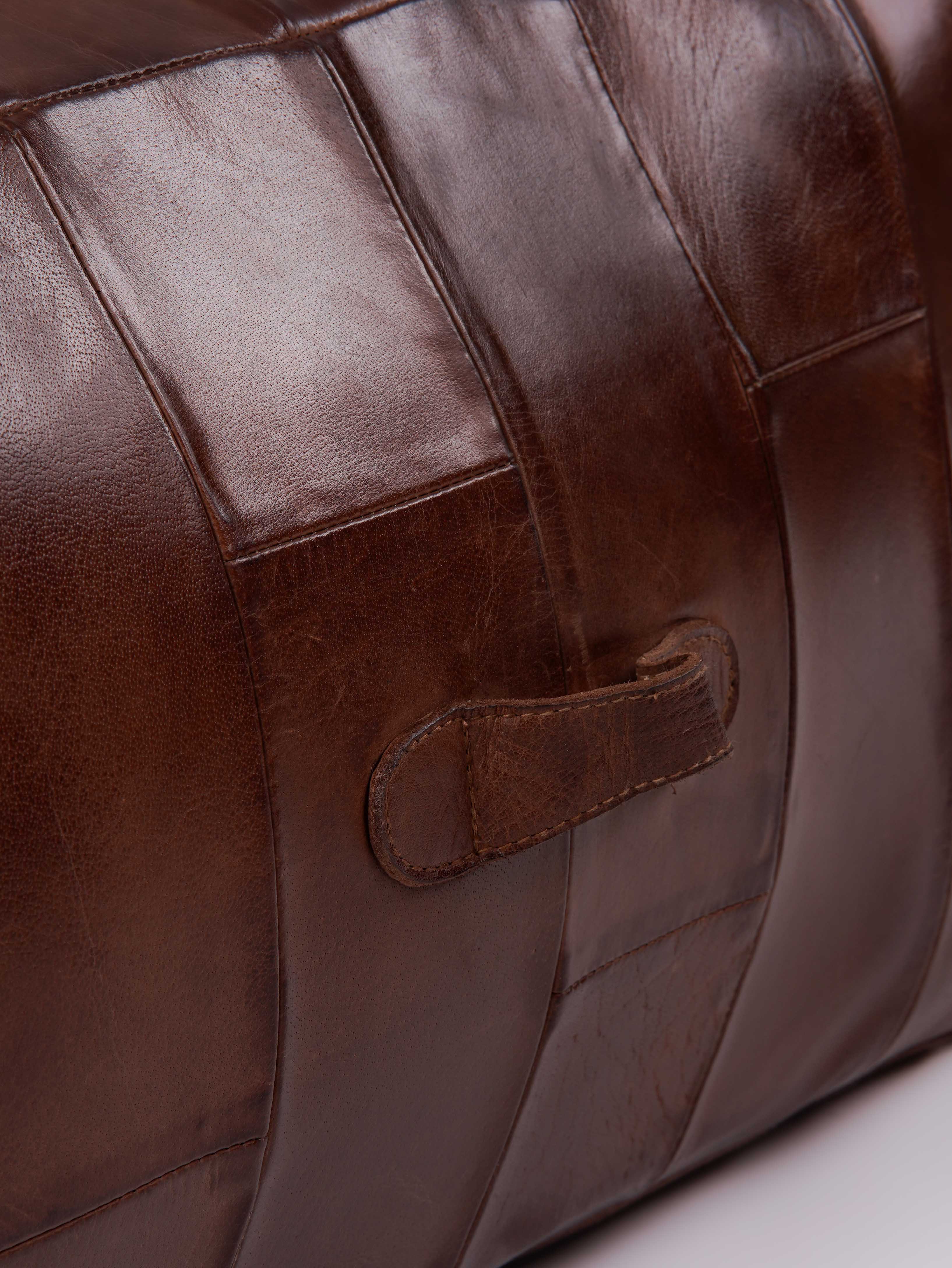 Detail of stitching and leather texture on cognac buffalo pouf