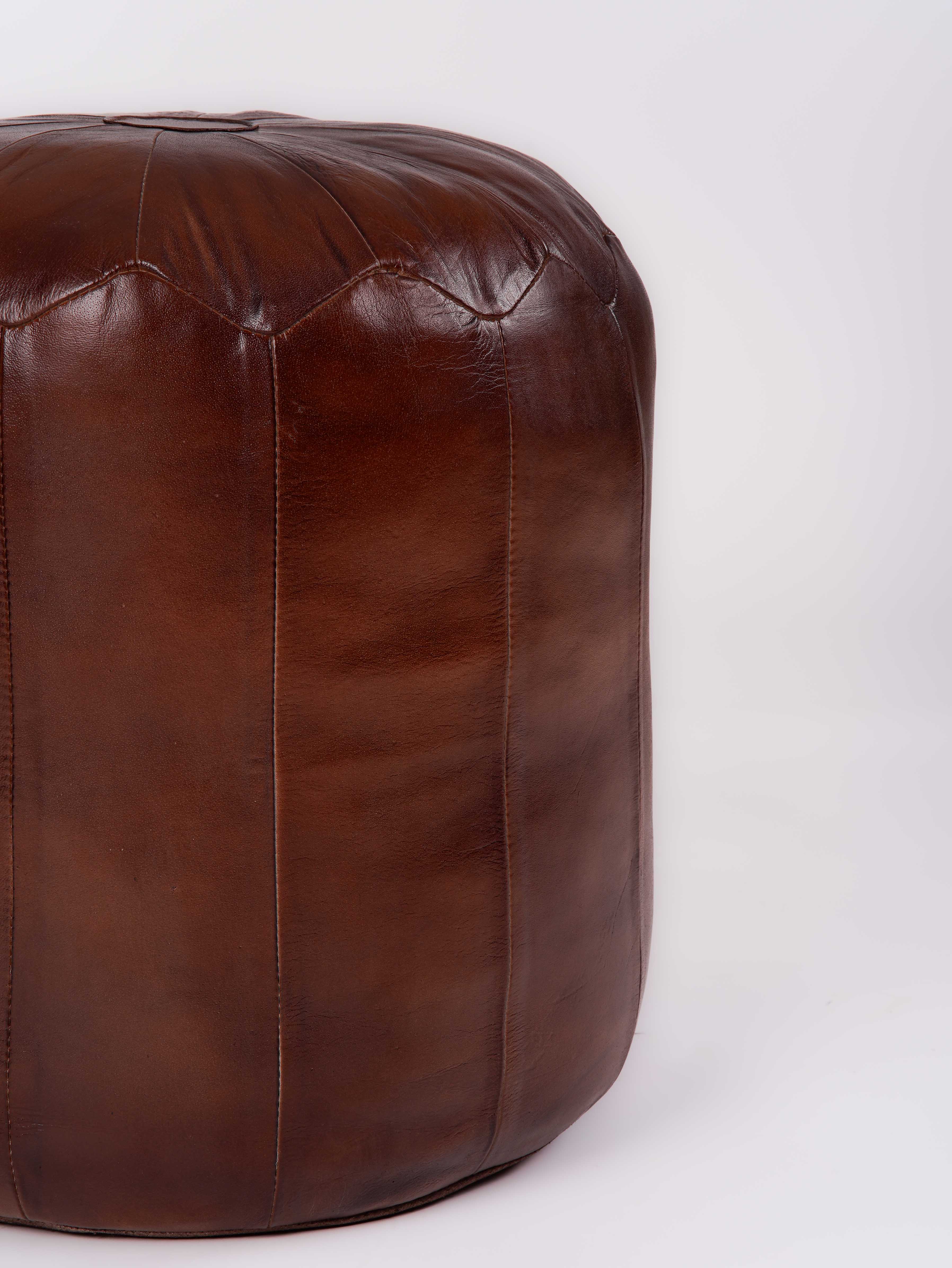 Structured leather pouf with panel stitching detail and warm brown tone