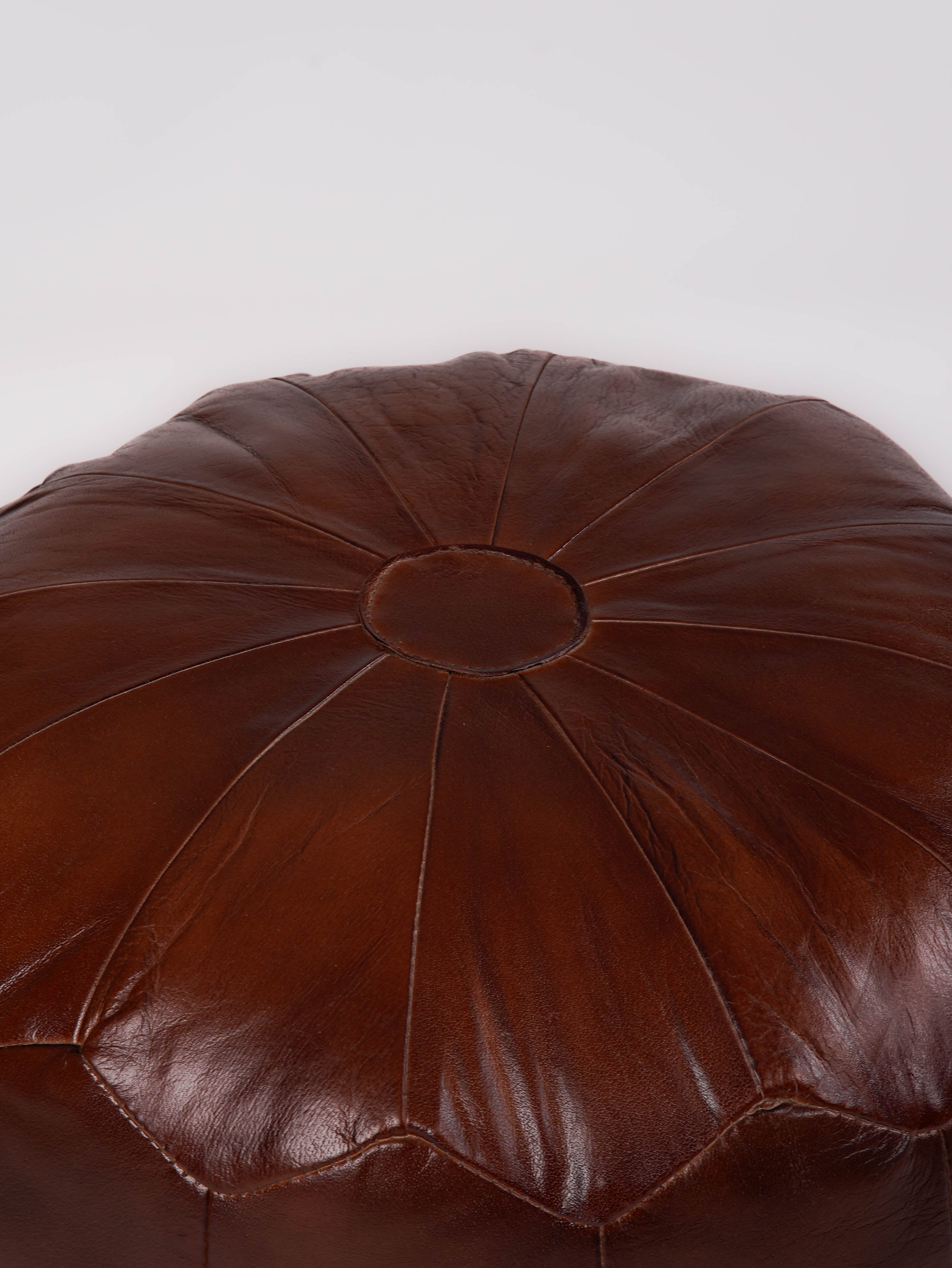 Structured leather pouf with panel stitching detail and warm brown tone