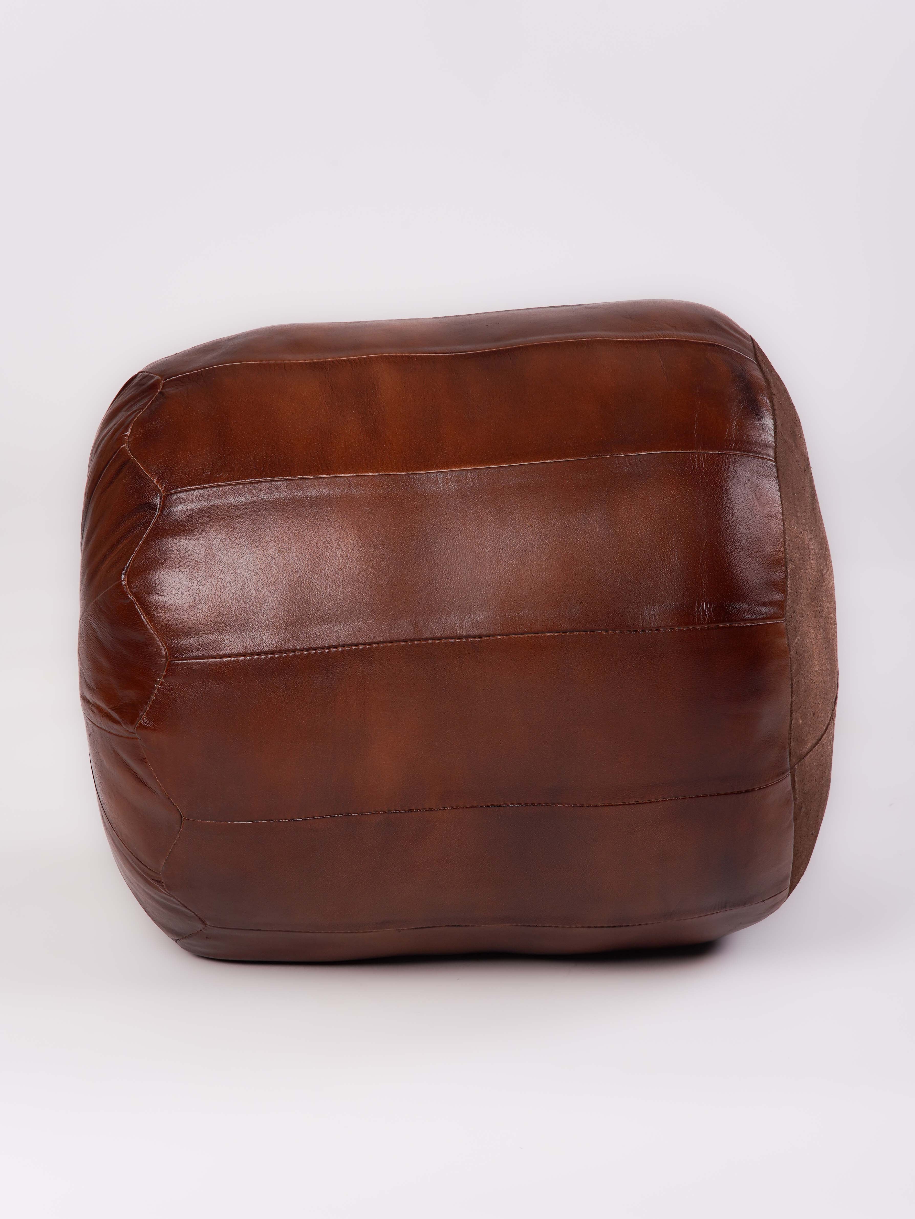 Structured leather pouf with panel stitching detail and warm brown tone