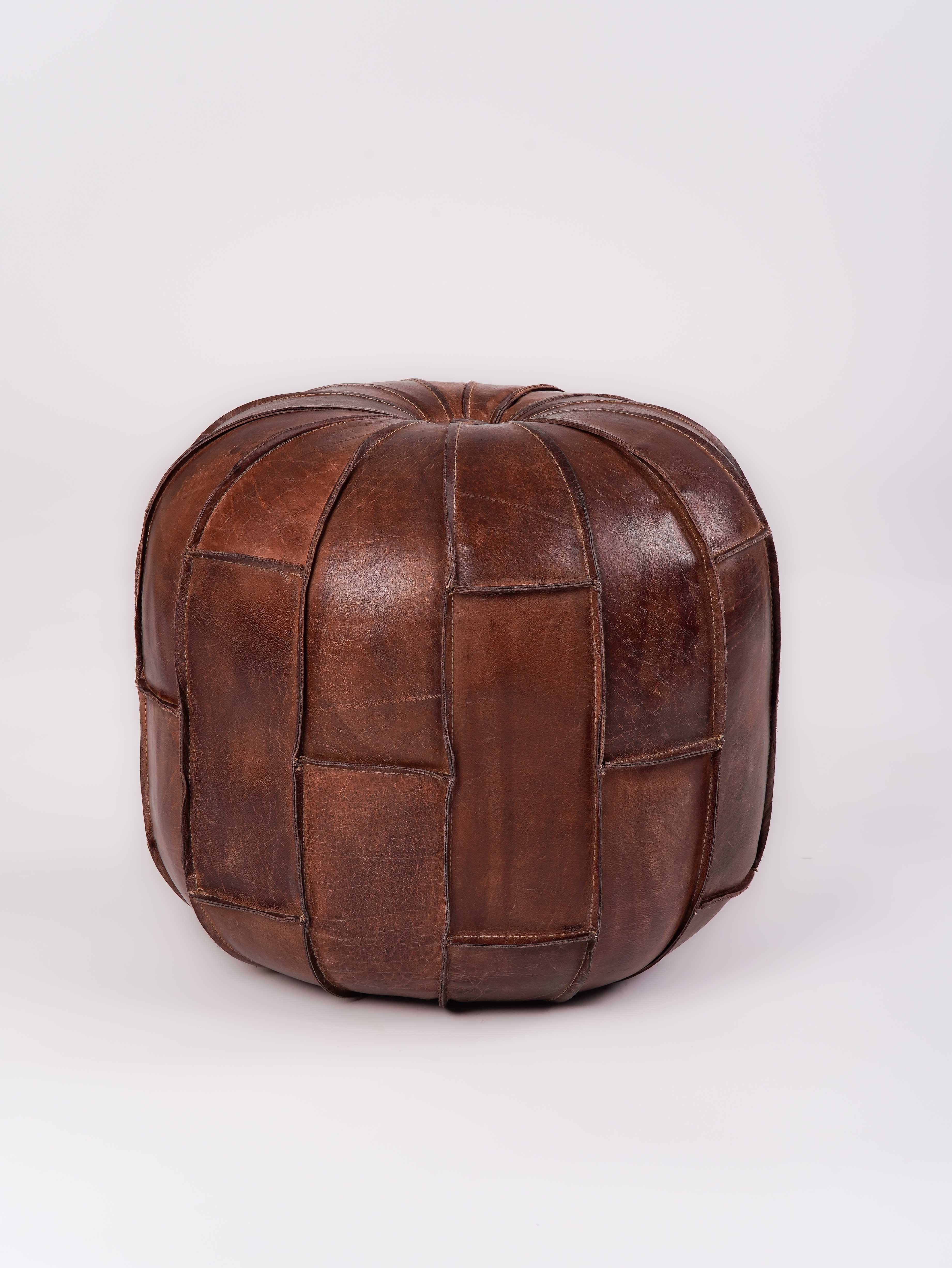 Structured round pouf in black buffalo leather next to beige sofa