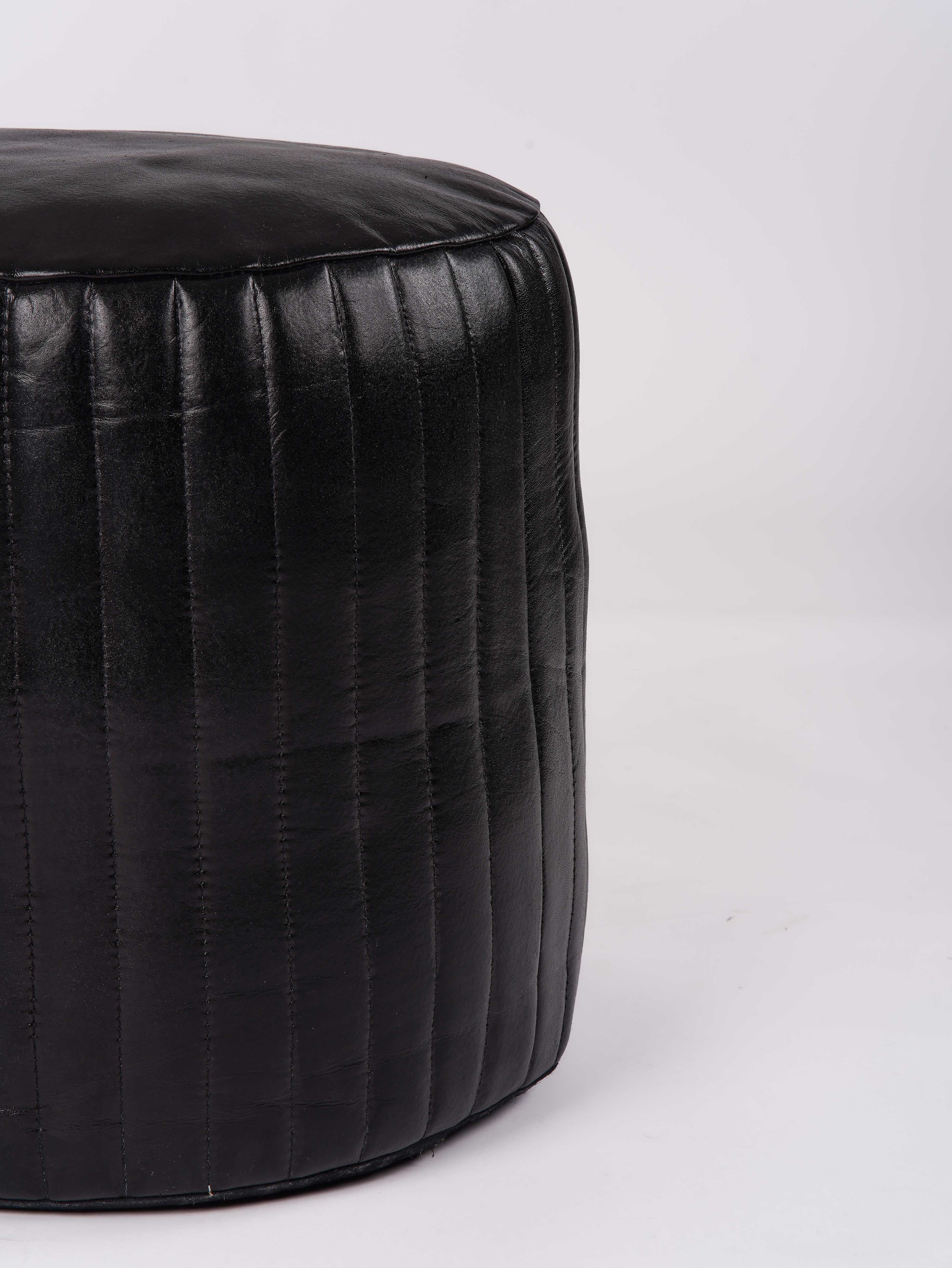 Detail of vertical stitching on black leather pouf surface