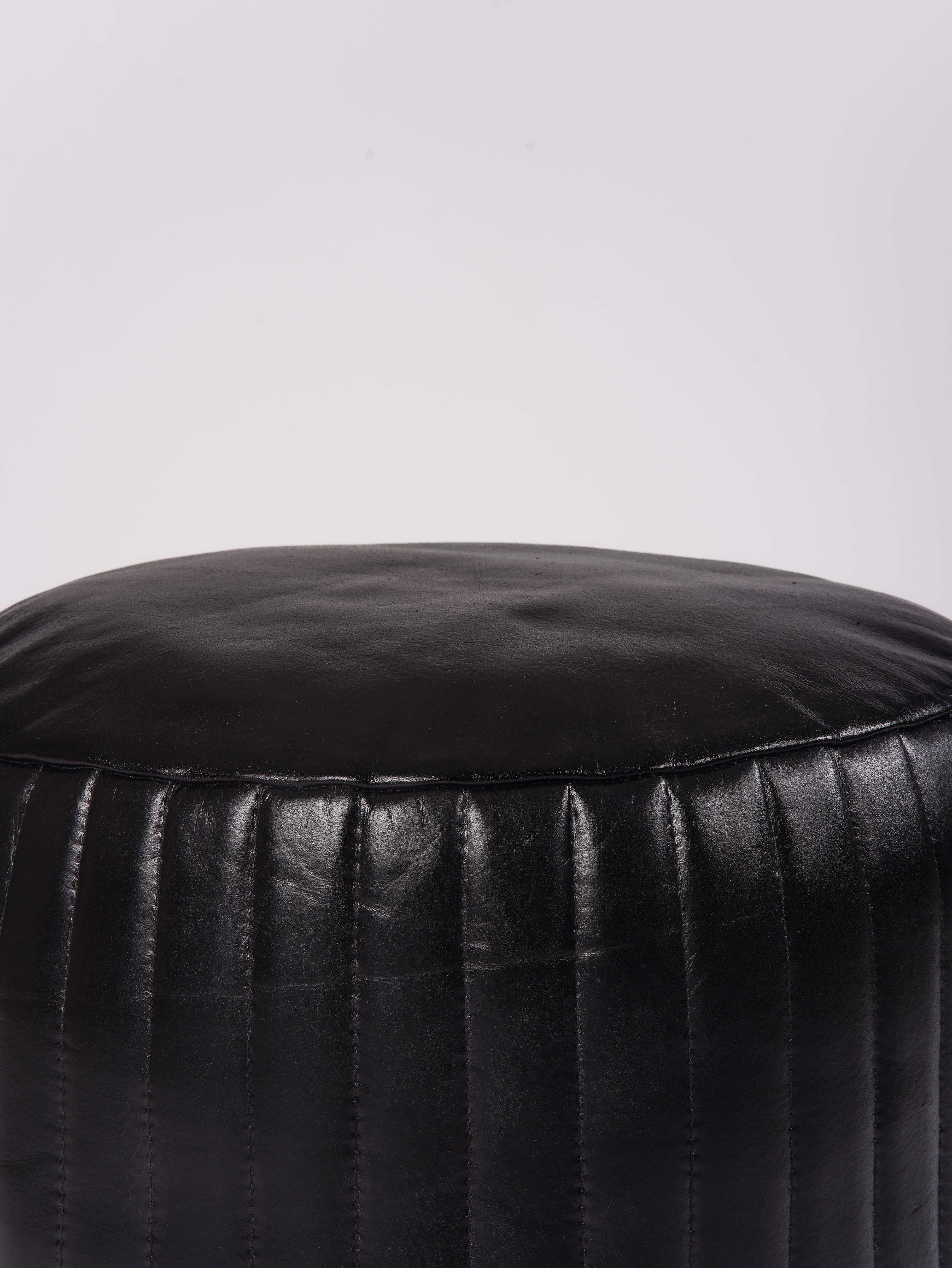 Detail of vertical stitching on black leather pouf surface