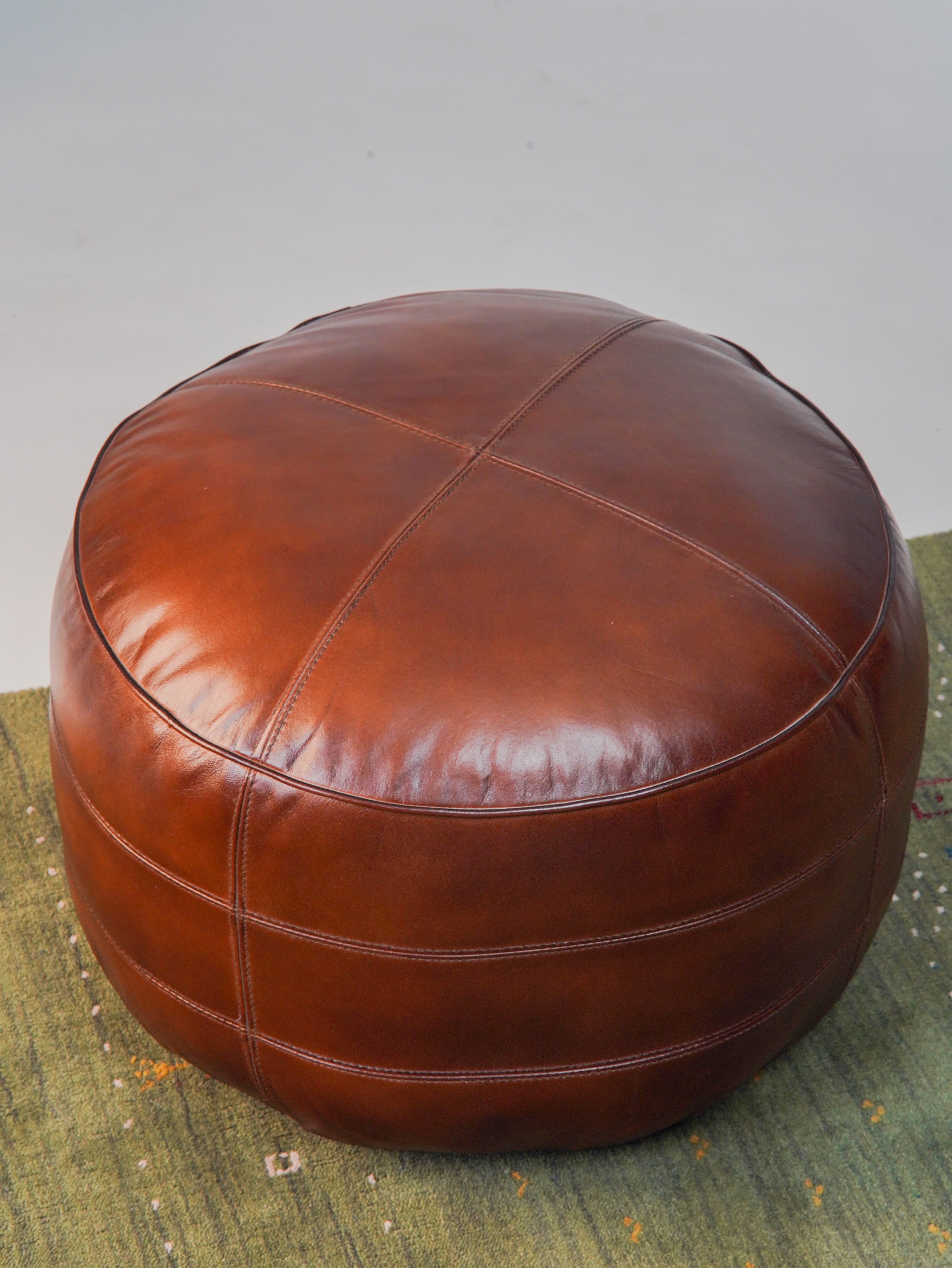 Top-down view of artisan-crafted leather pouf with center stitching