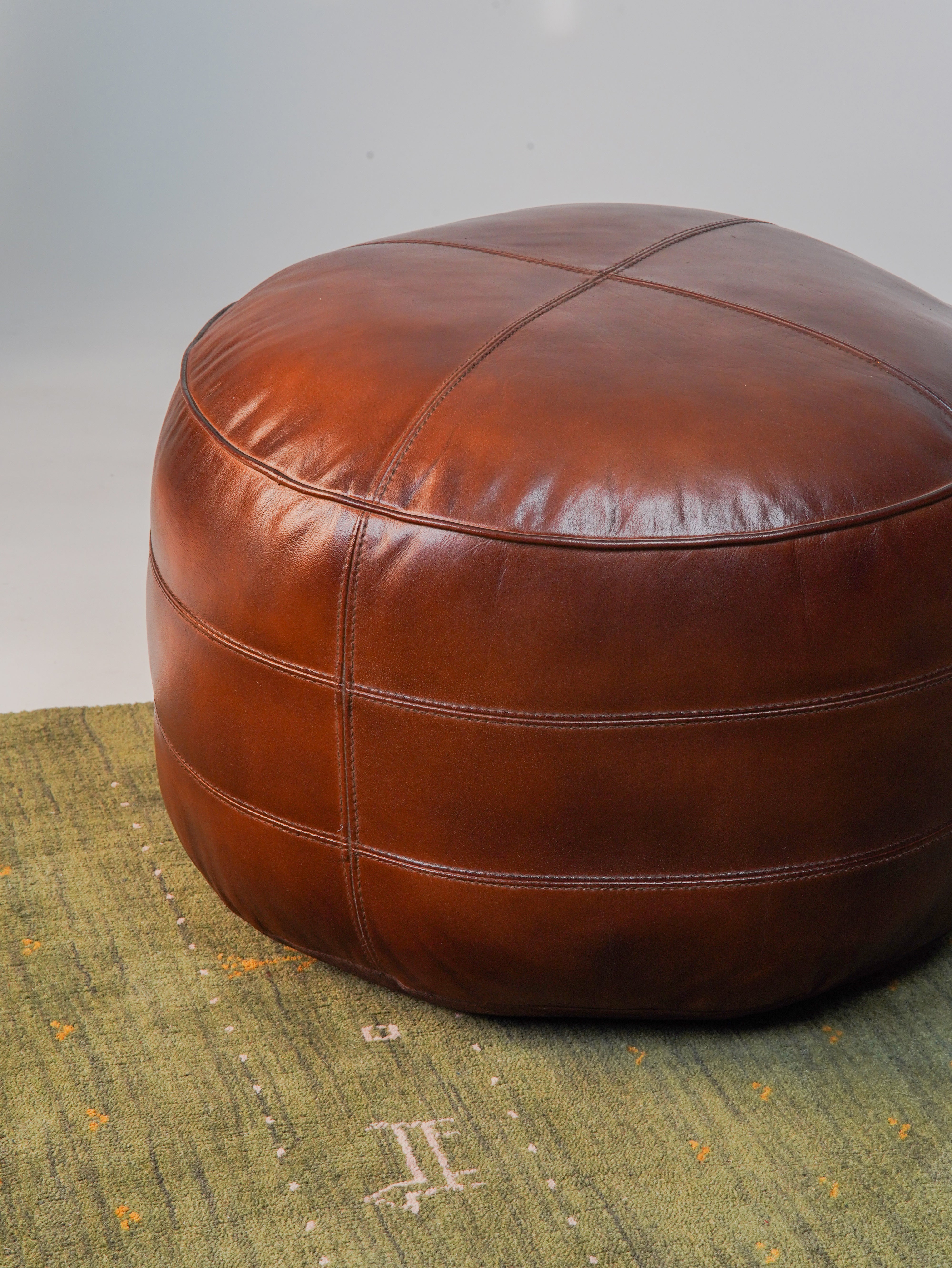 Top-down view of artisan-crafted leather pouf with center stitching