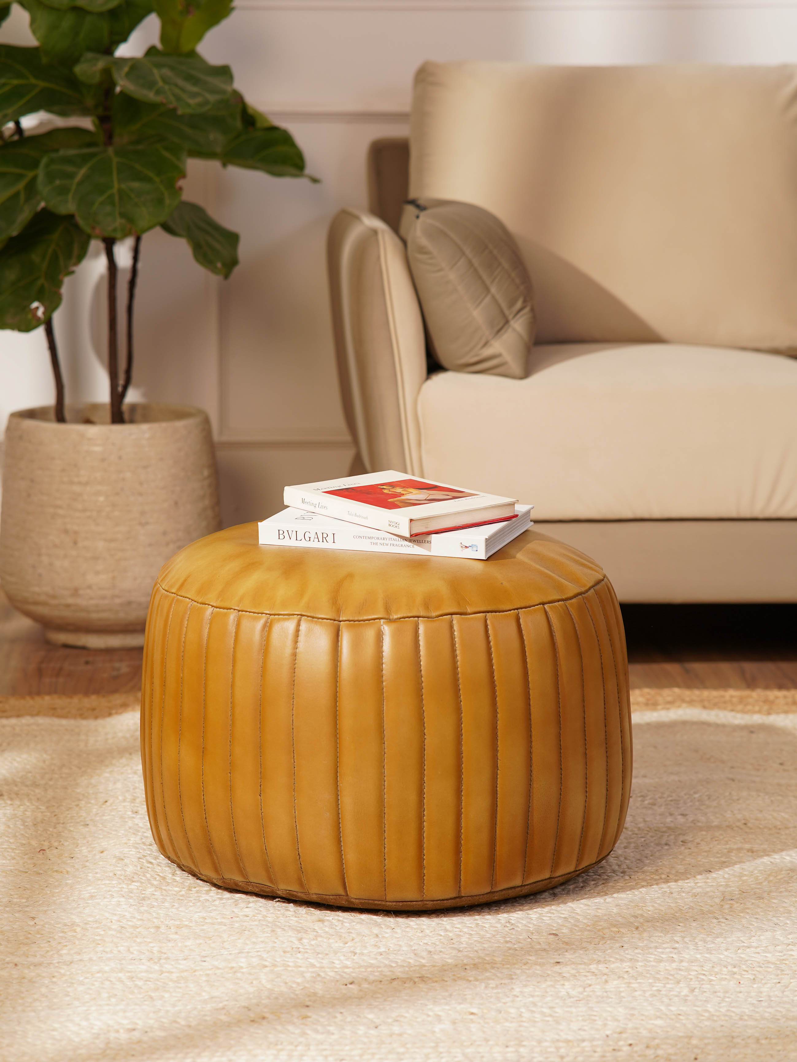 Round beige buffalo leather pouf in modern living room beside sofa