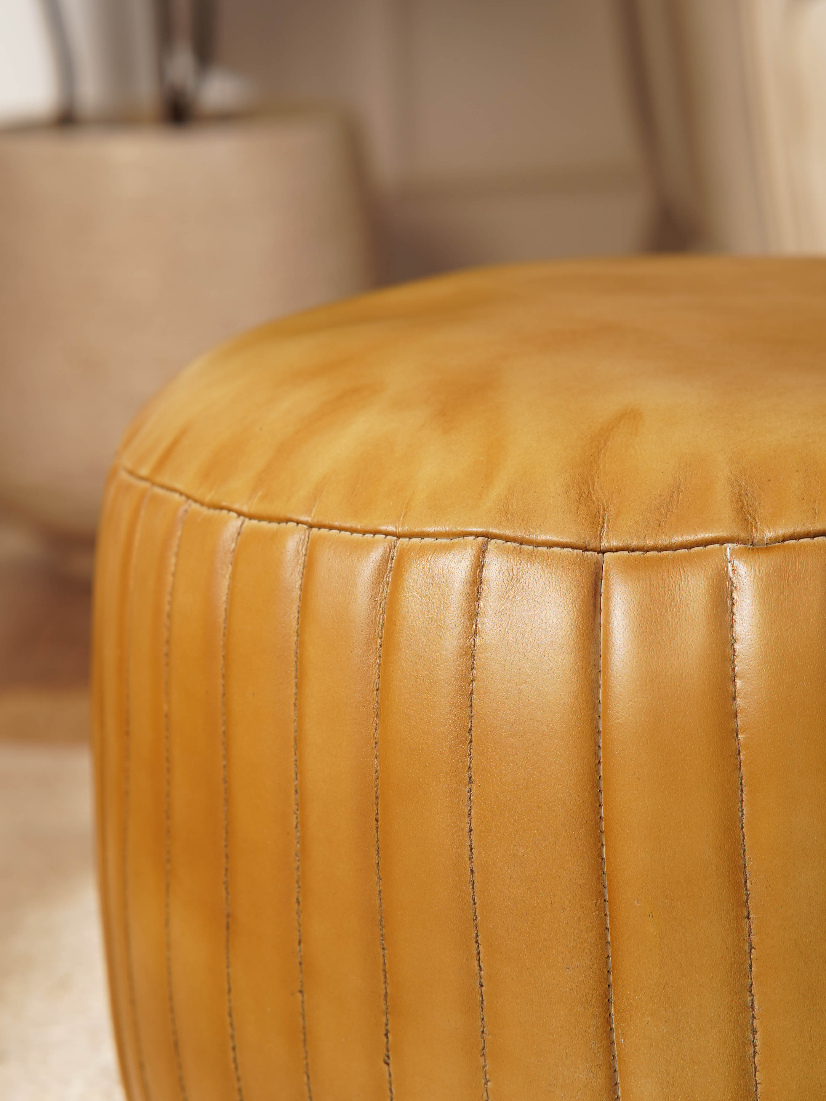 Detail of stitching and full grain leather texture on beige pouf