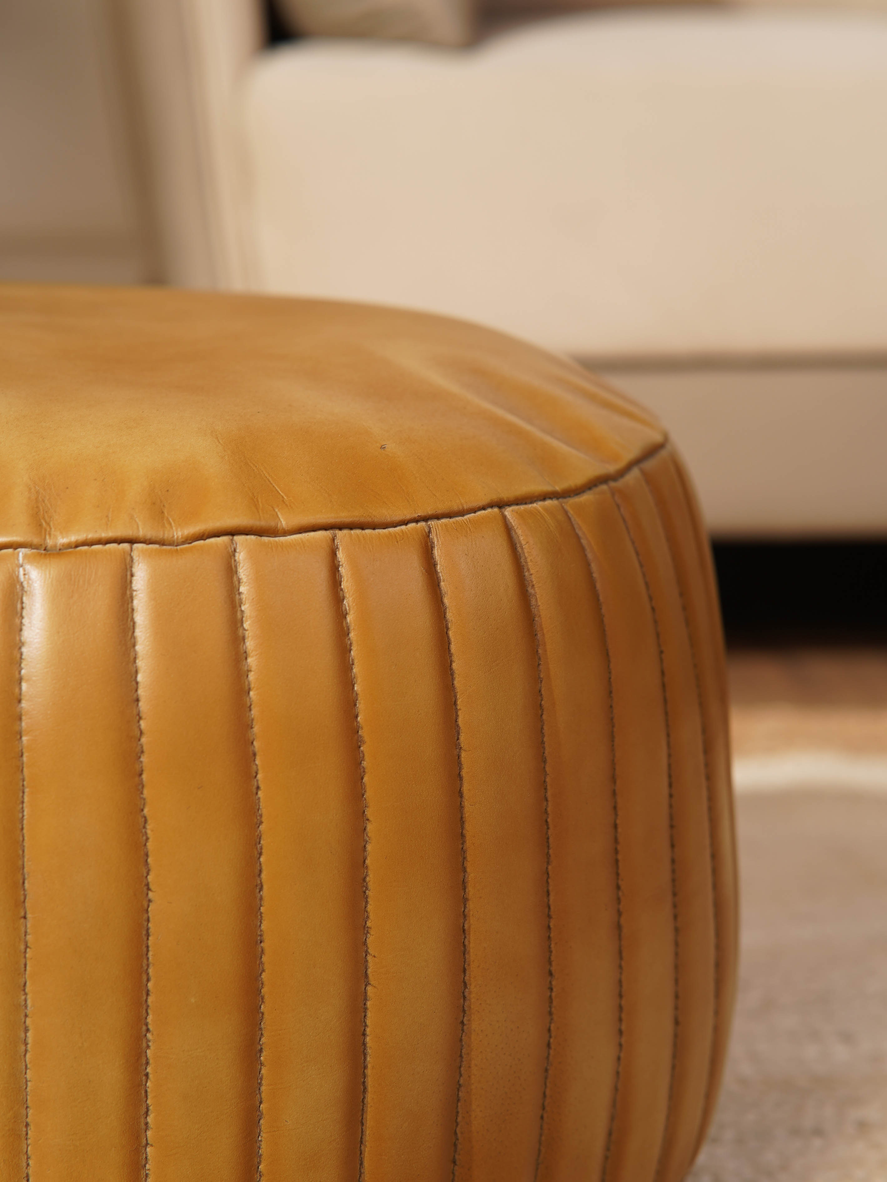 Detail of stitching and full grain leather texture on beige pouf