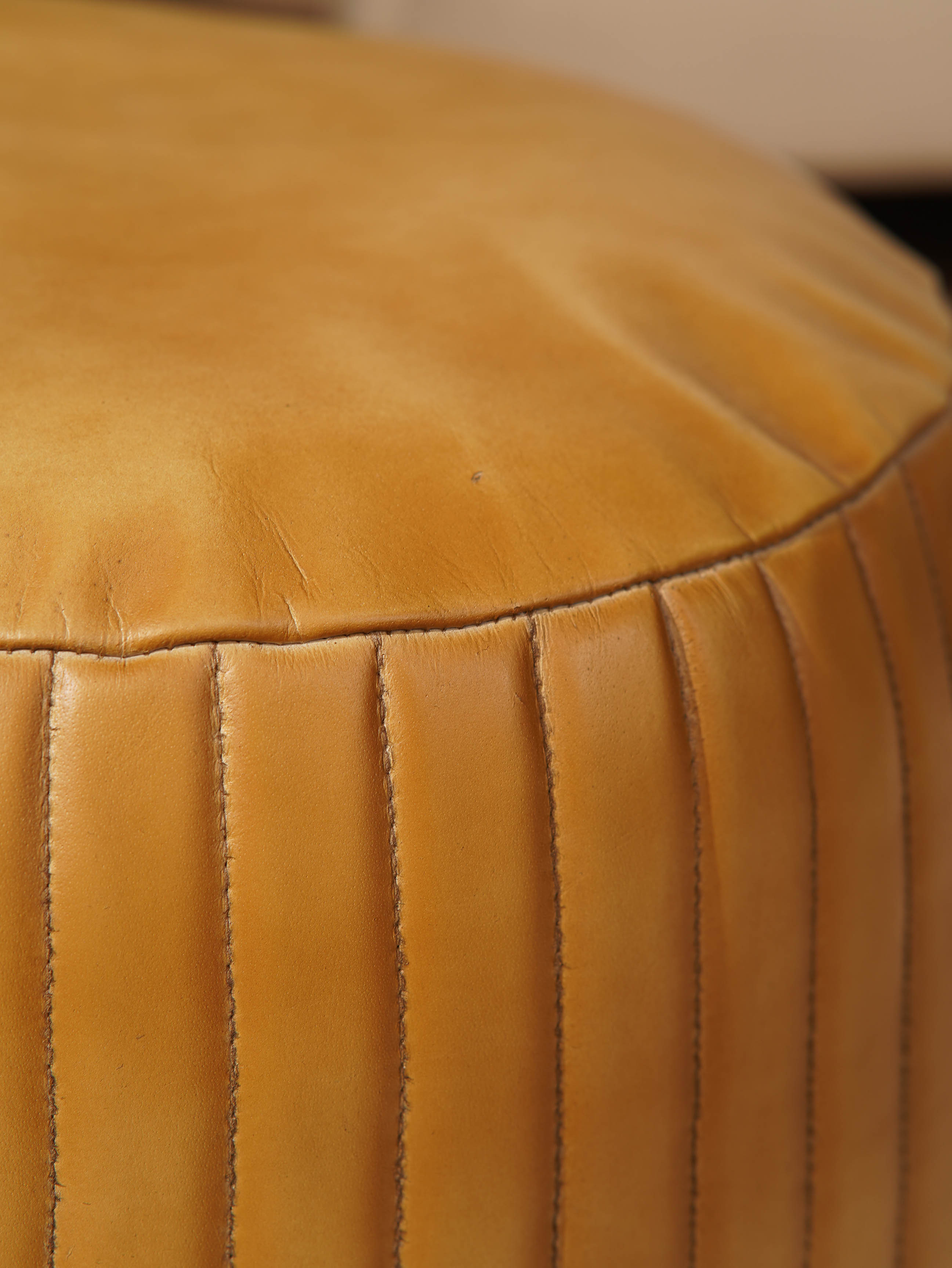 Detail of stitching and full grain leather texture on beige pouf