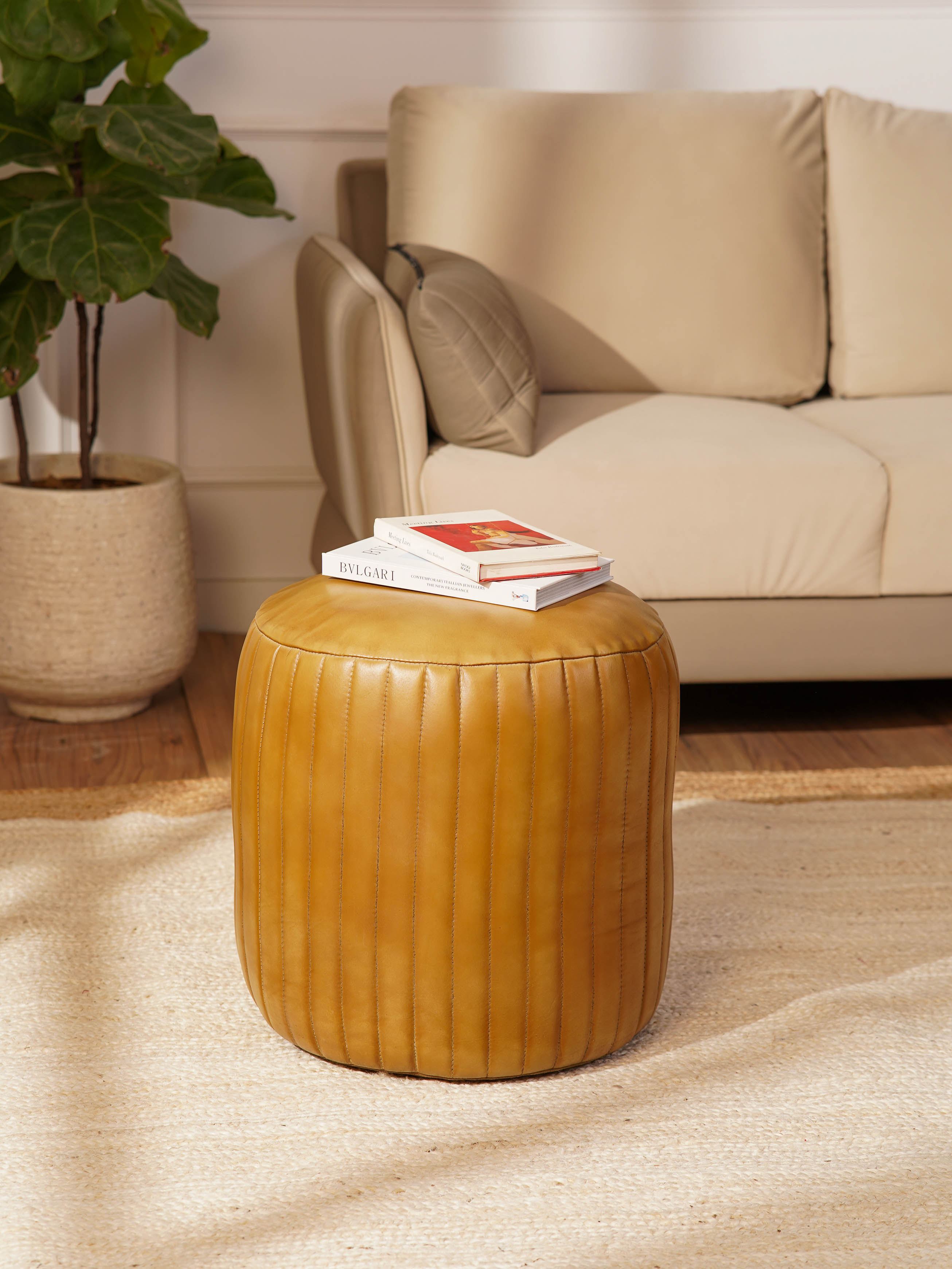 Round beige buffalo leather pouf in modern living room beside sofa