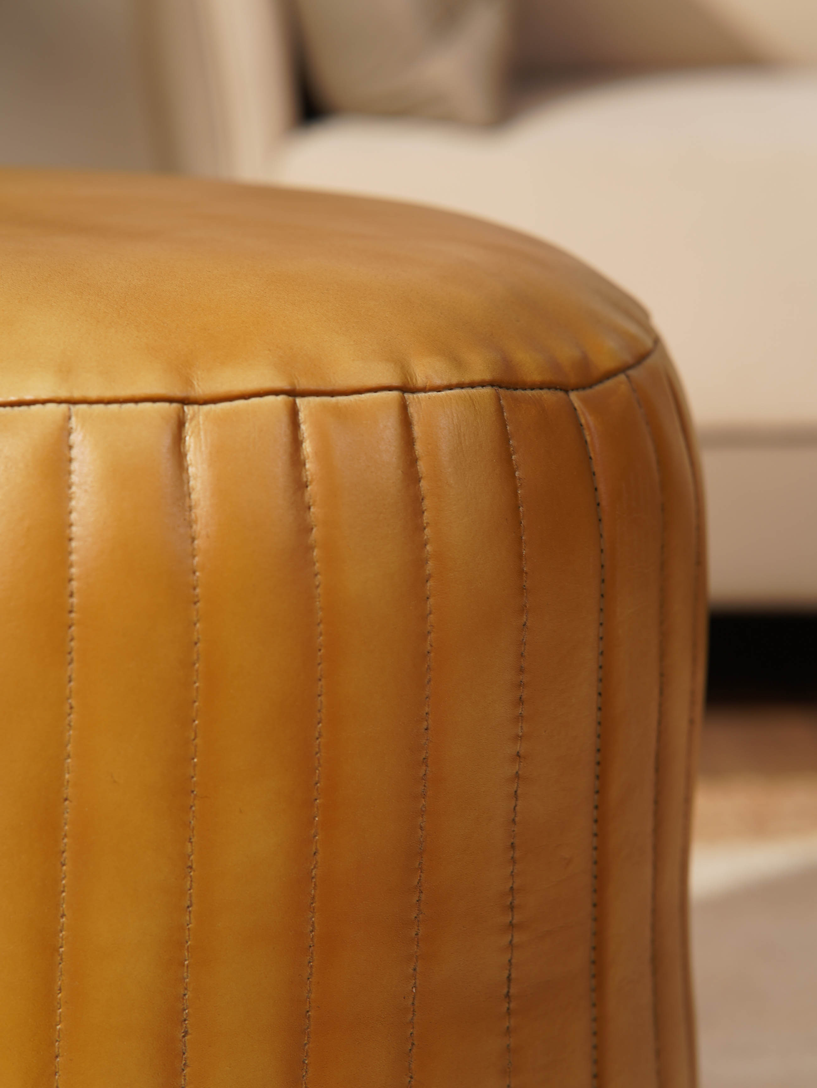 Detail of stitching and full grain leather texture on beige pouf