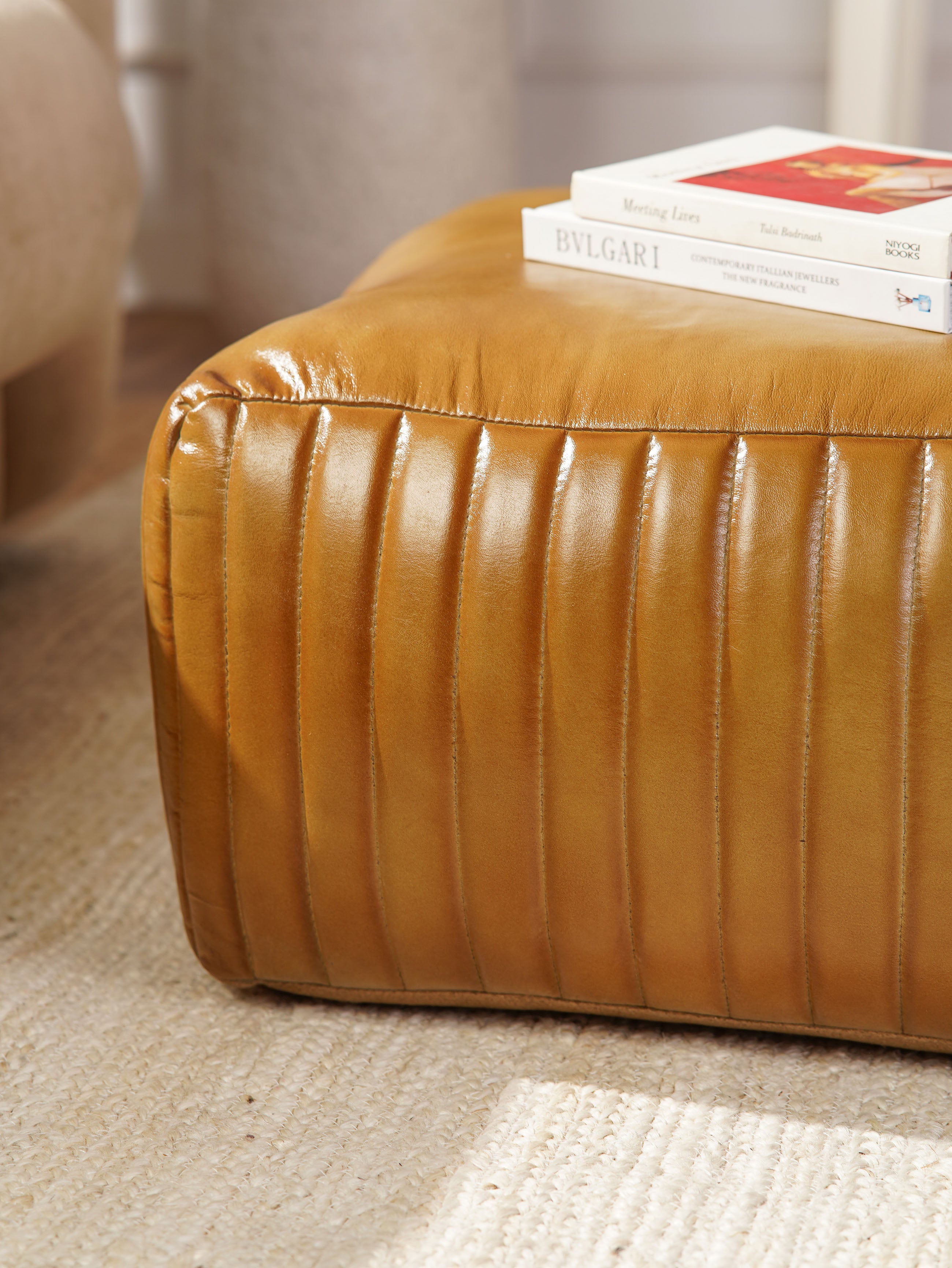 Close-up of stitched vertical pleats on beige buffalo leather pouf