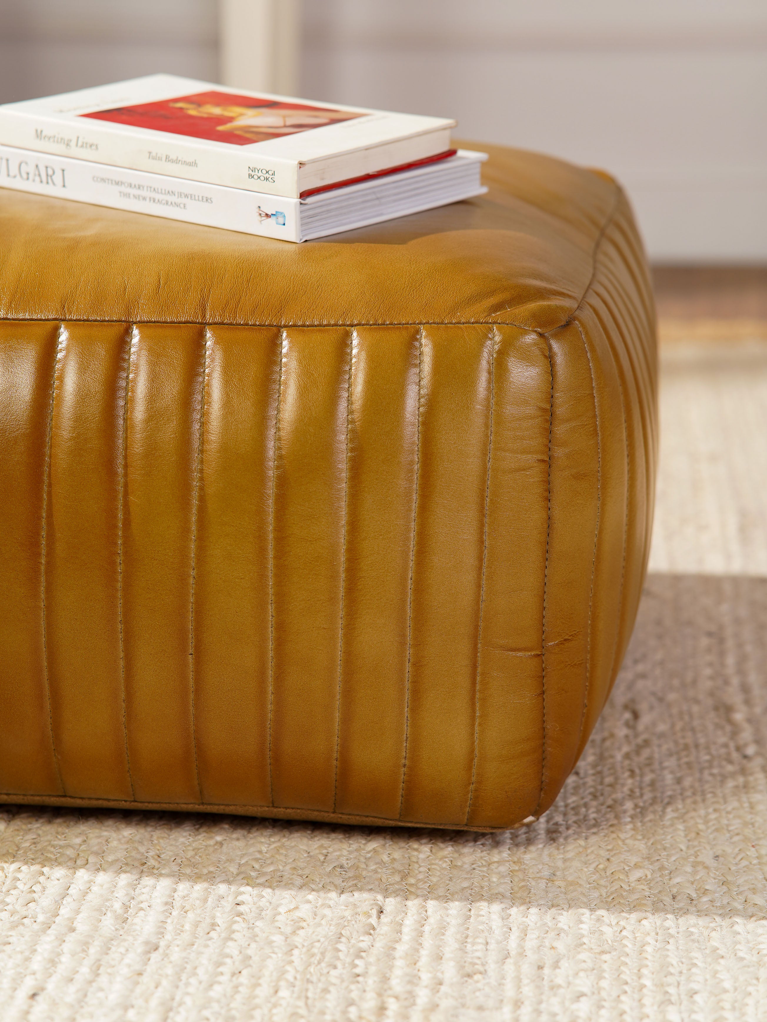 Close-up of stitched vertical pleats on beige buffalo leather pouf
