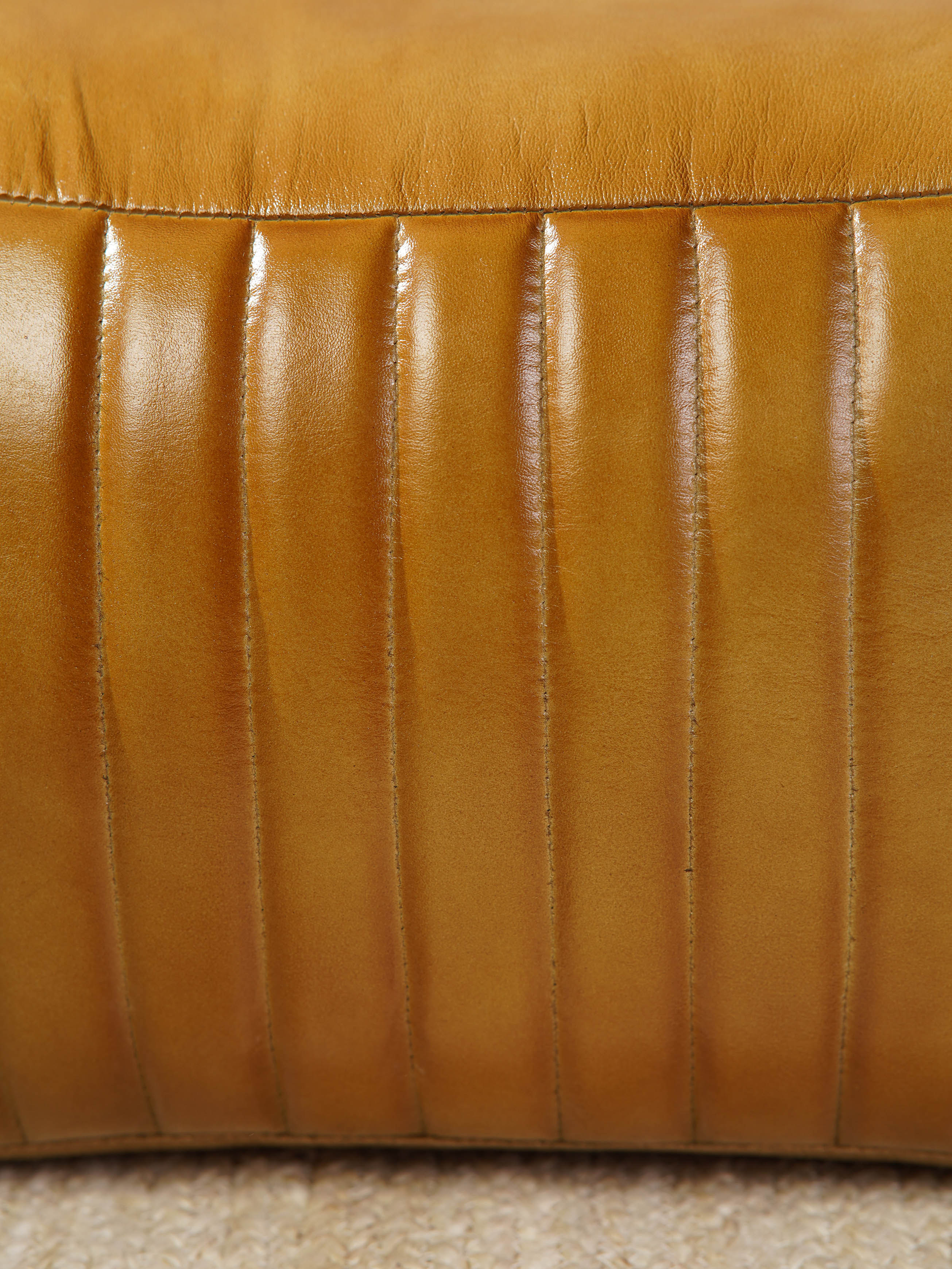 Close-up of stitched vertical pleats on beige buffalo leather pouf