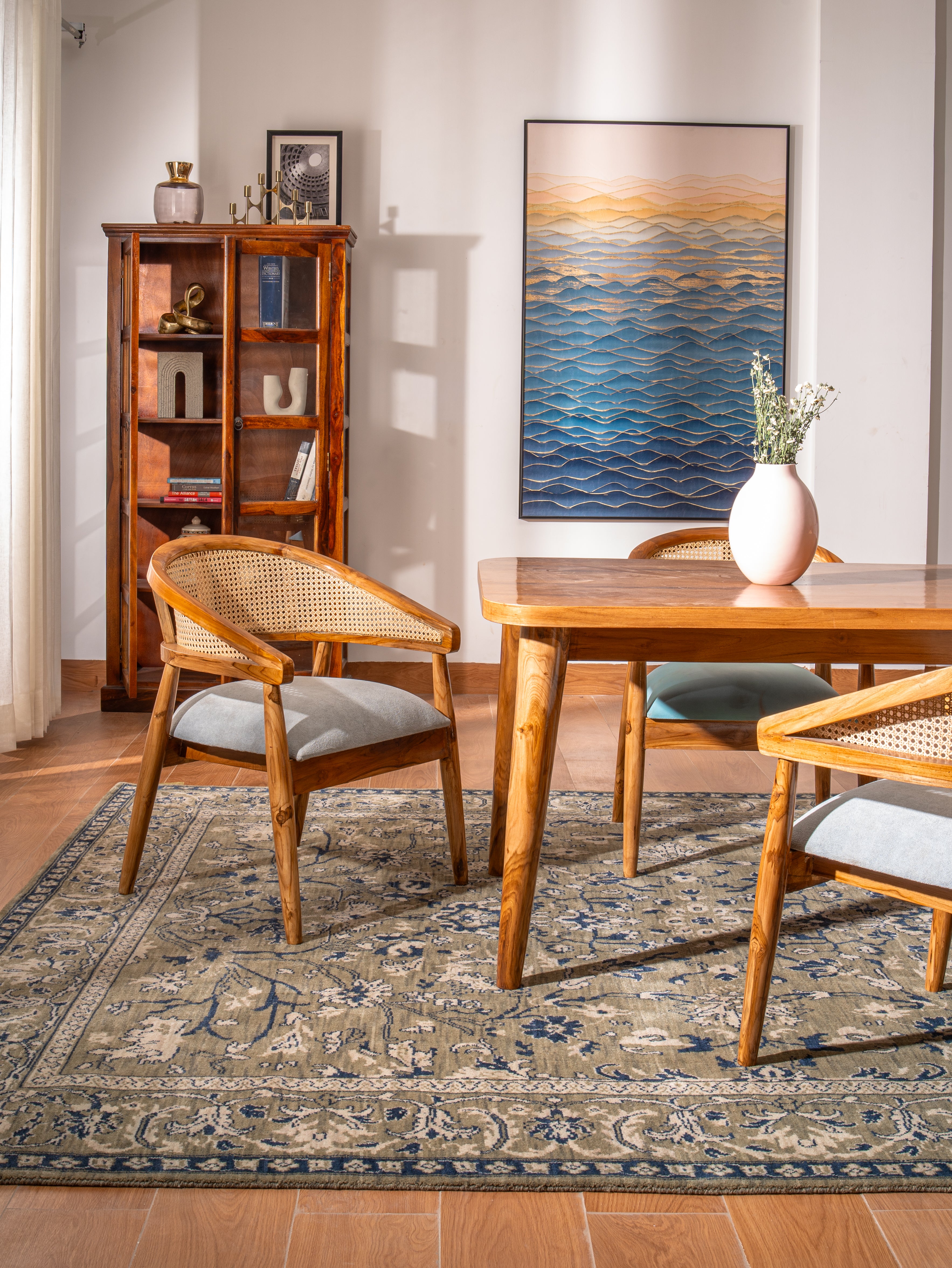 Wooden dining table with chairs in a room with a bookshelf and wall art.
