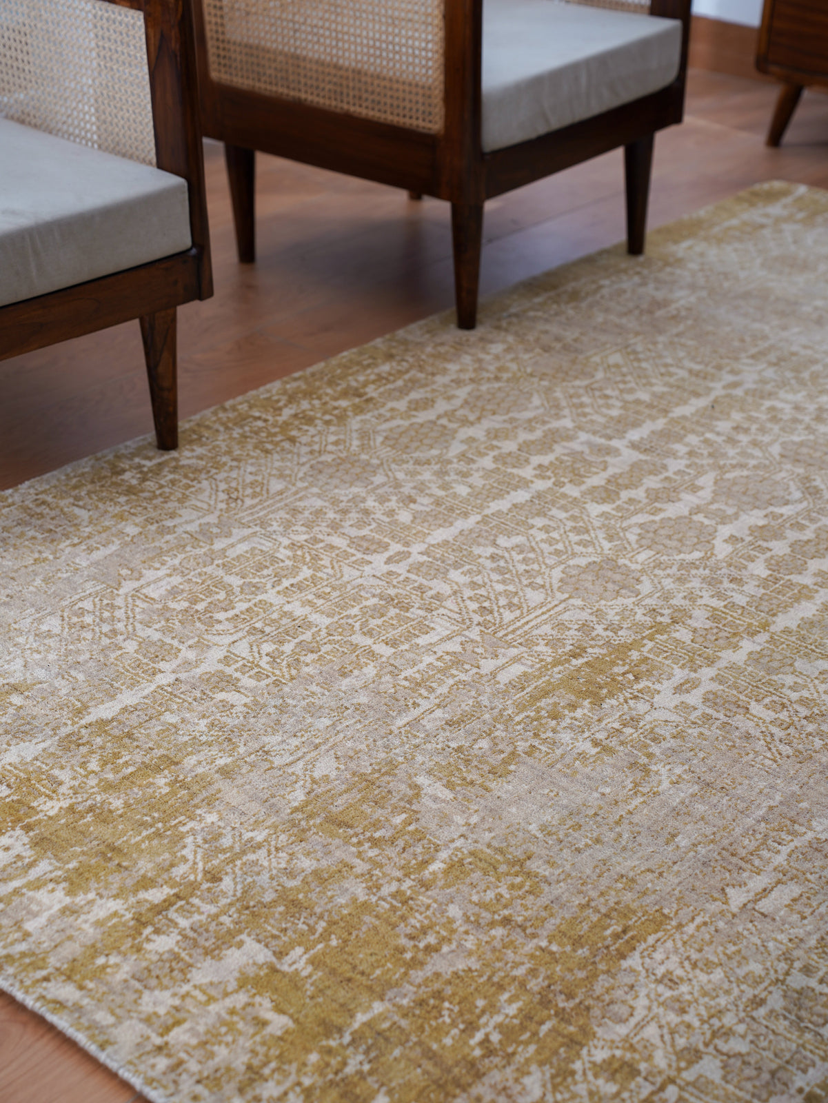 Patterned rug on a wooden floor with chairs in the background