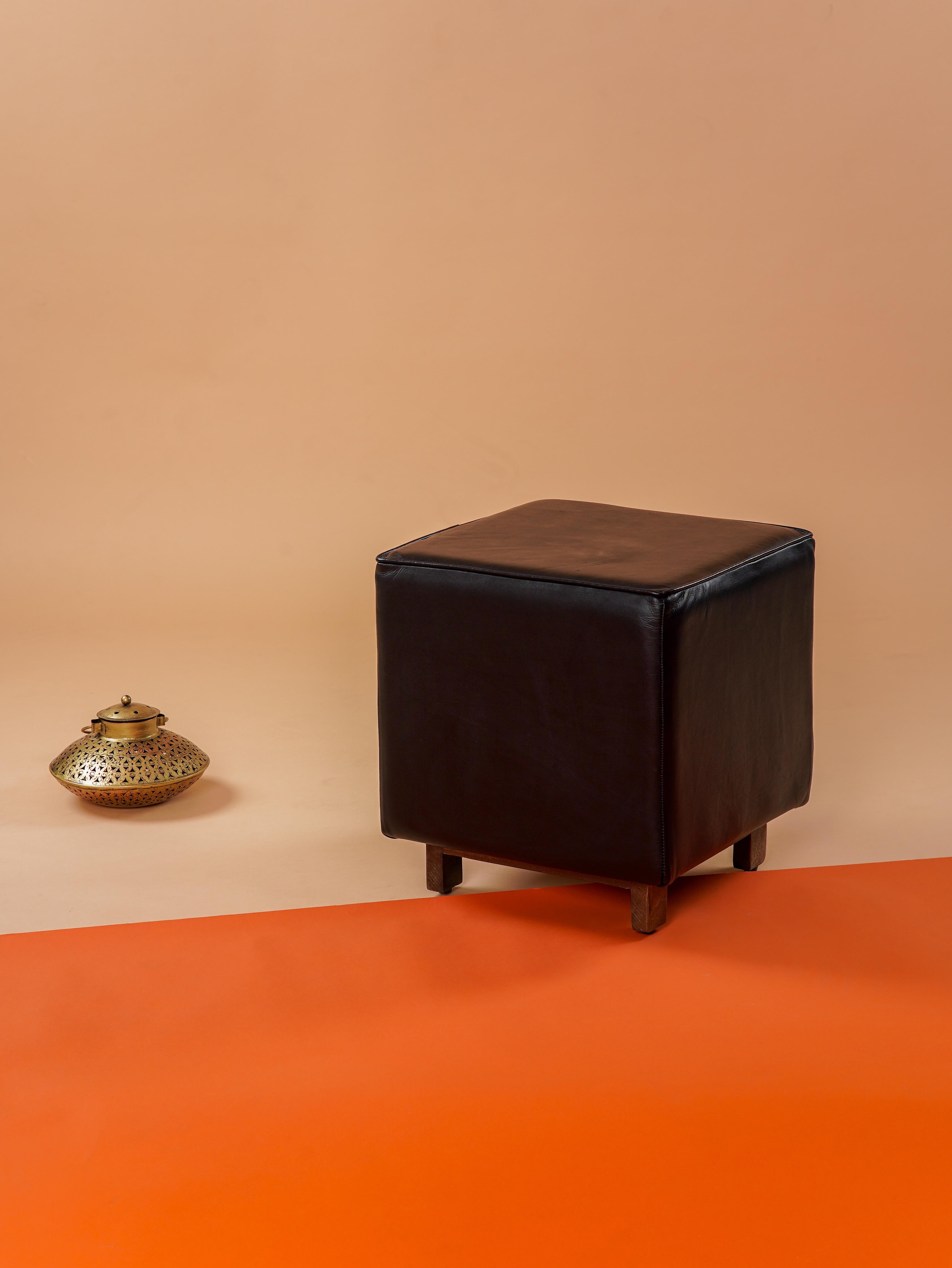 Black buffalo leather stool with wooden legs in minimalist room