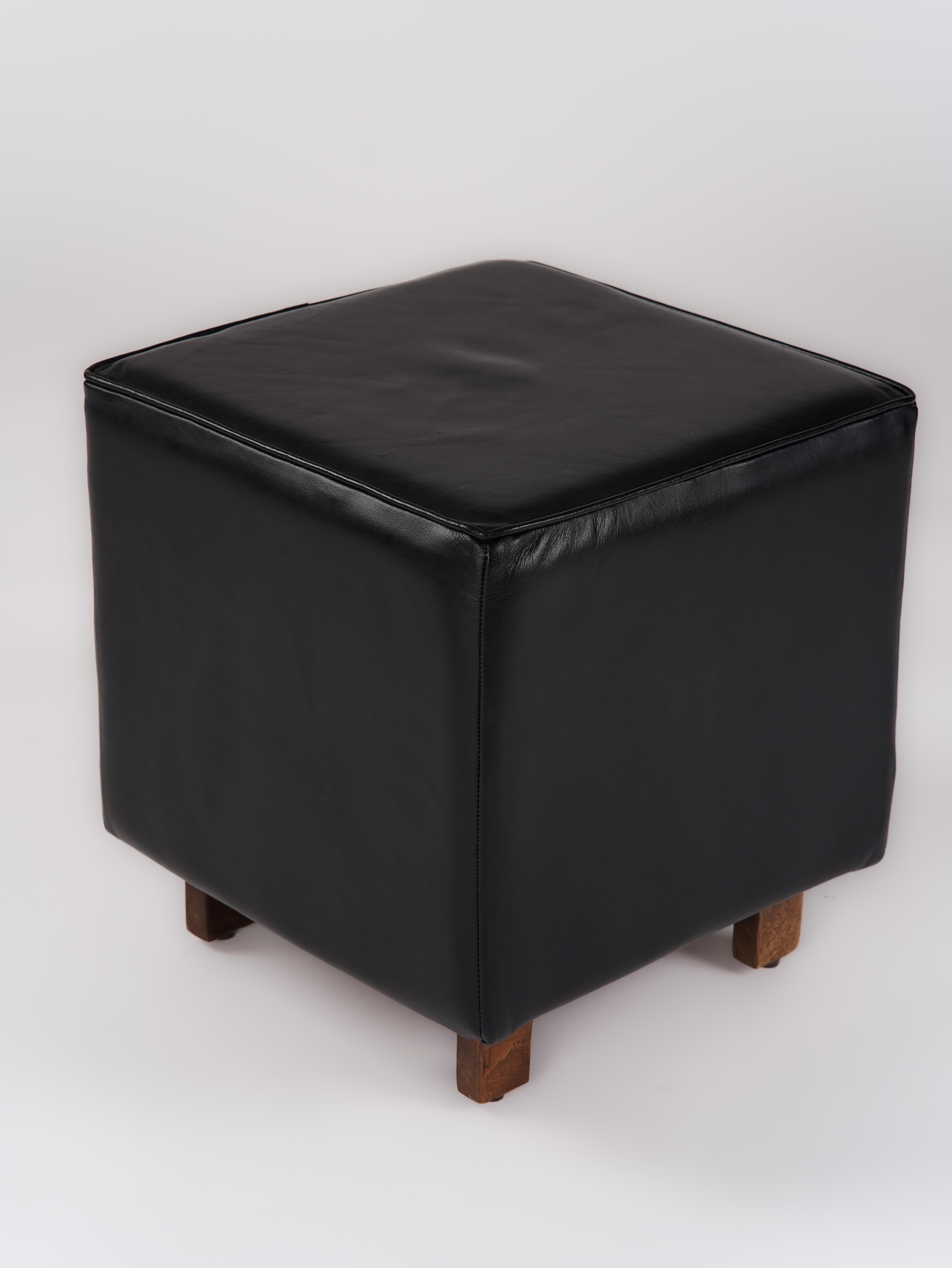 Black buffalo leather stool with wooden legs in minimalist room