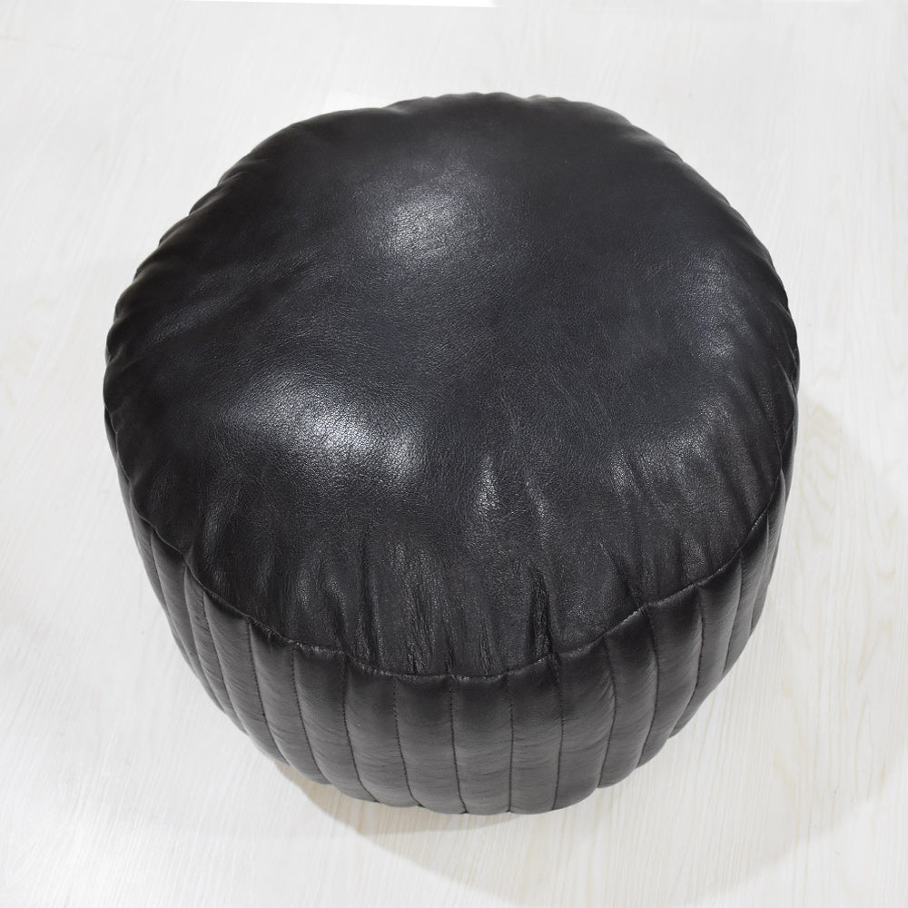 Top-down view of hand-stitched leather pouf with slight padding and grain