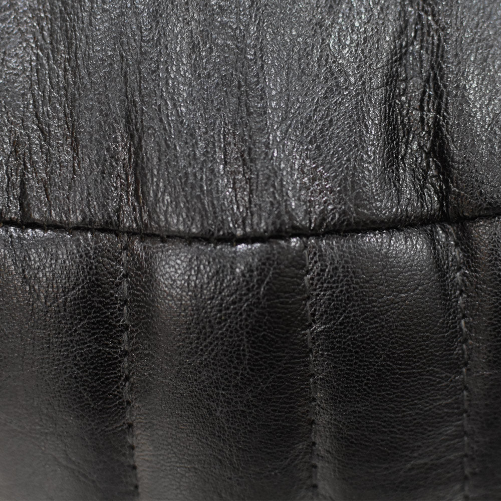 Detail of vertical stitching on black leather pouf surface
