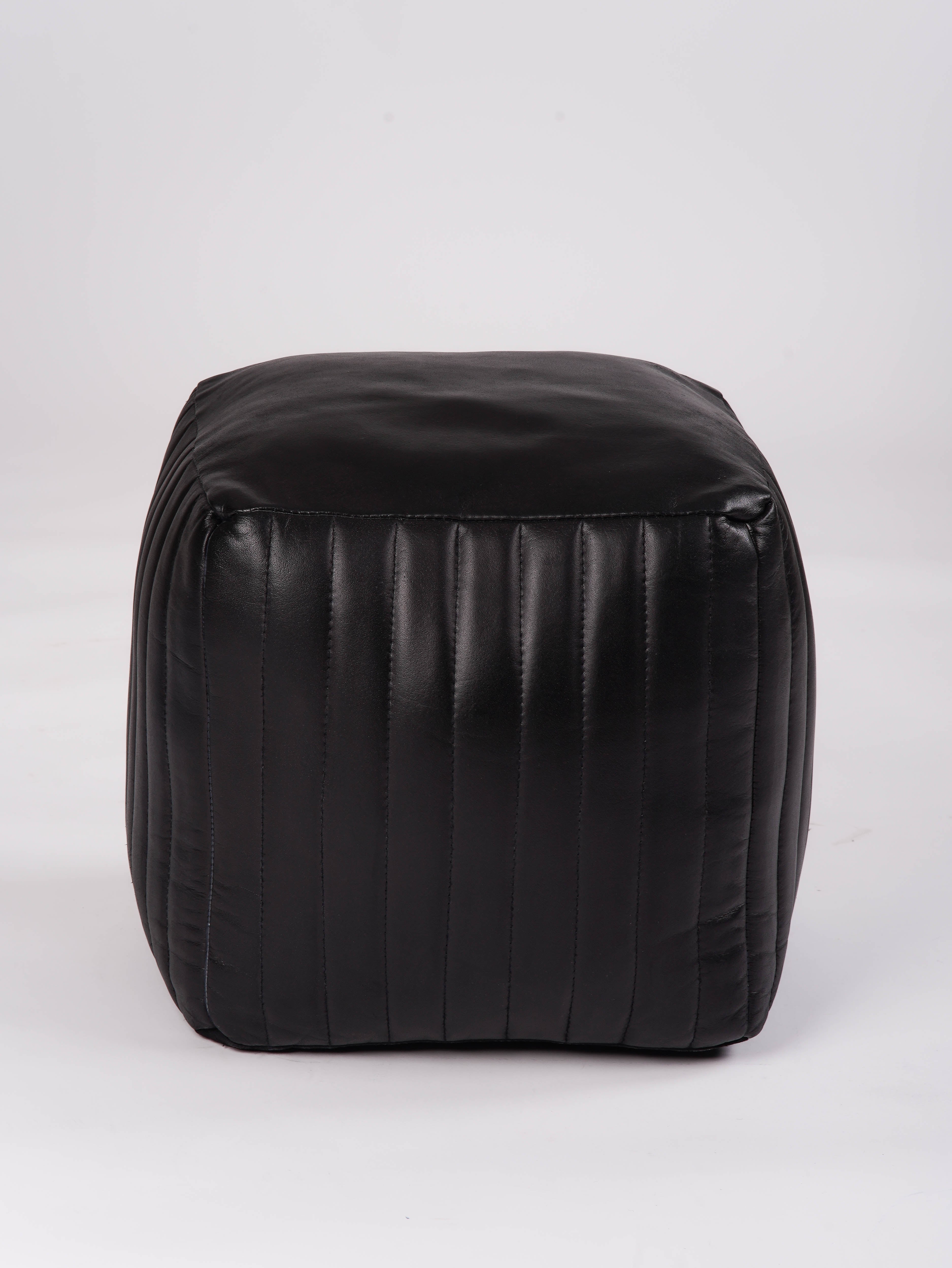 Side view of black leather pouf with vertical stitched panels
