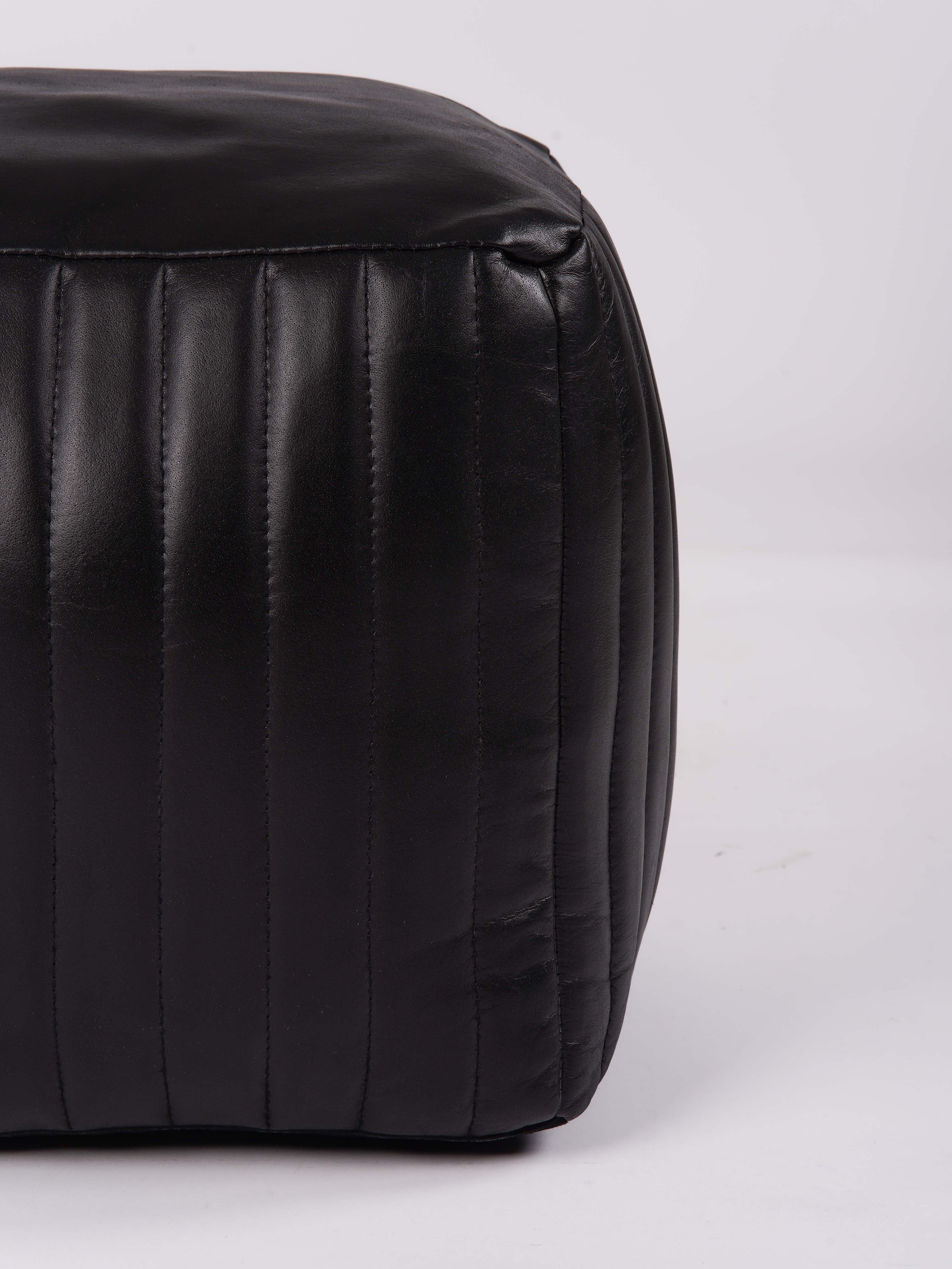 Detail shot of stitching and leather texture on square pouf

