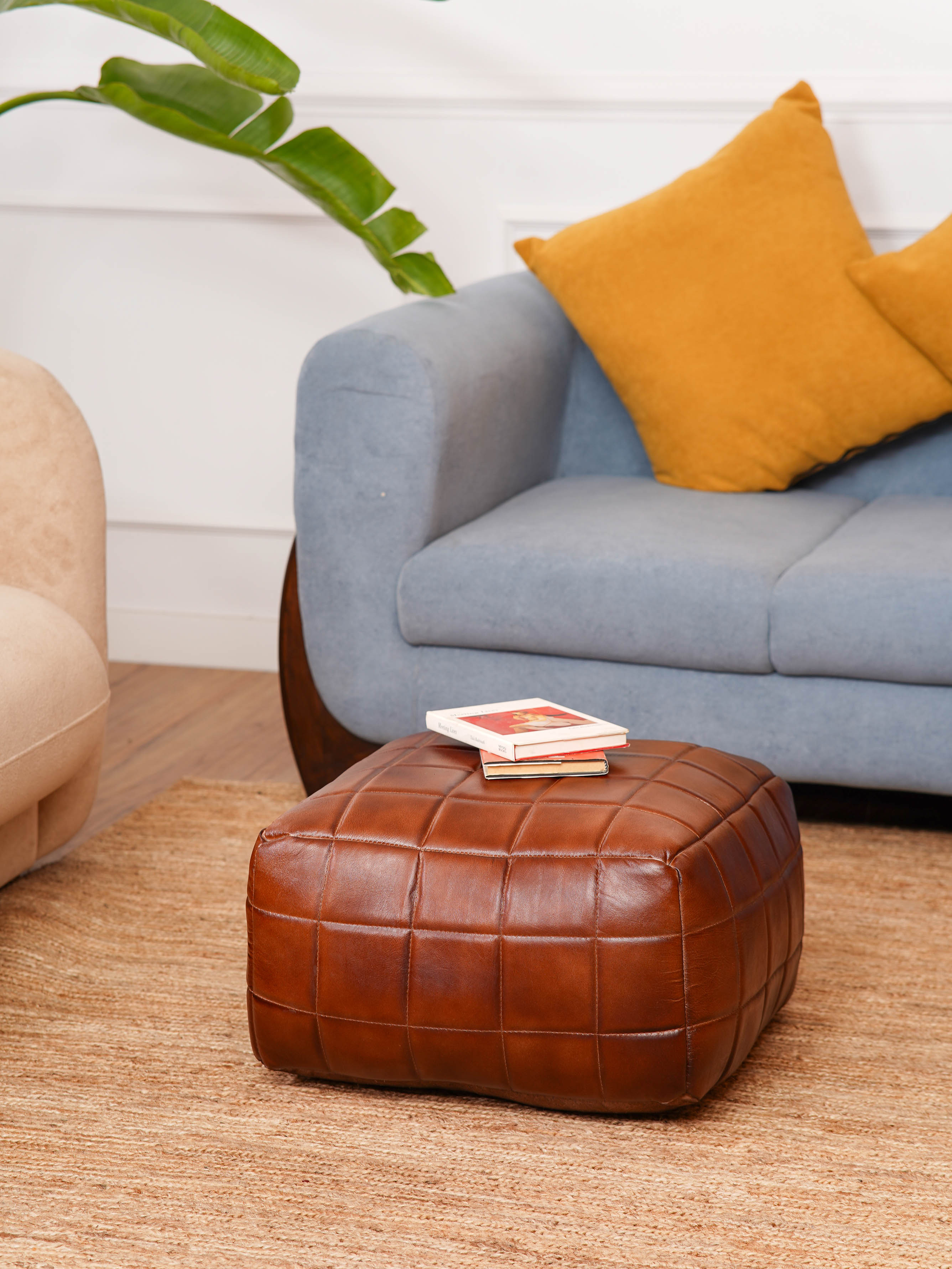 Brown leather square pouf beside modern blue armchair
