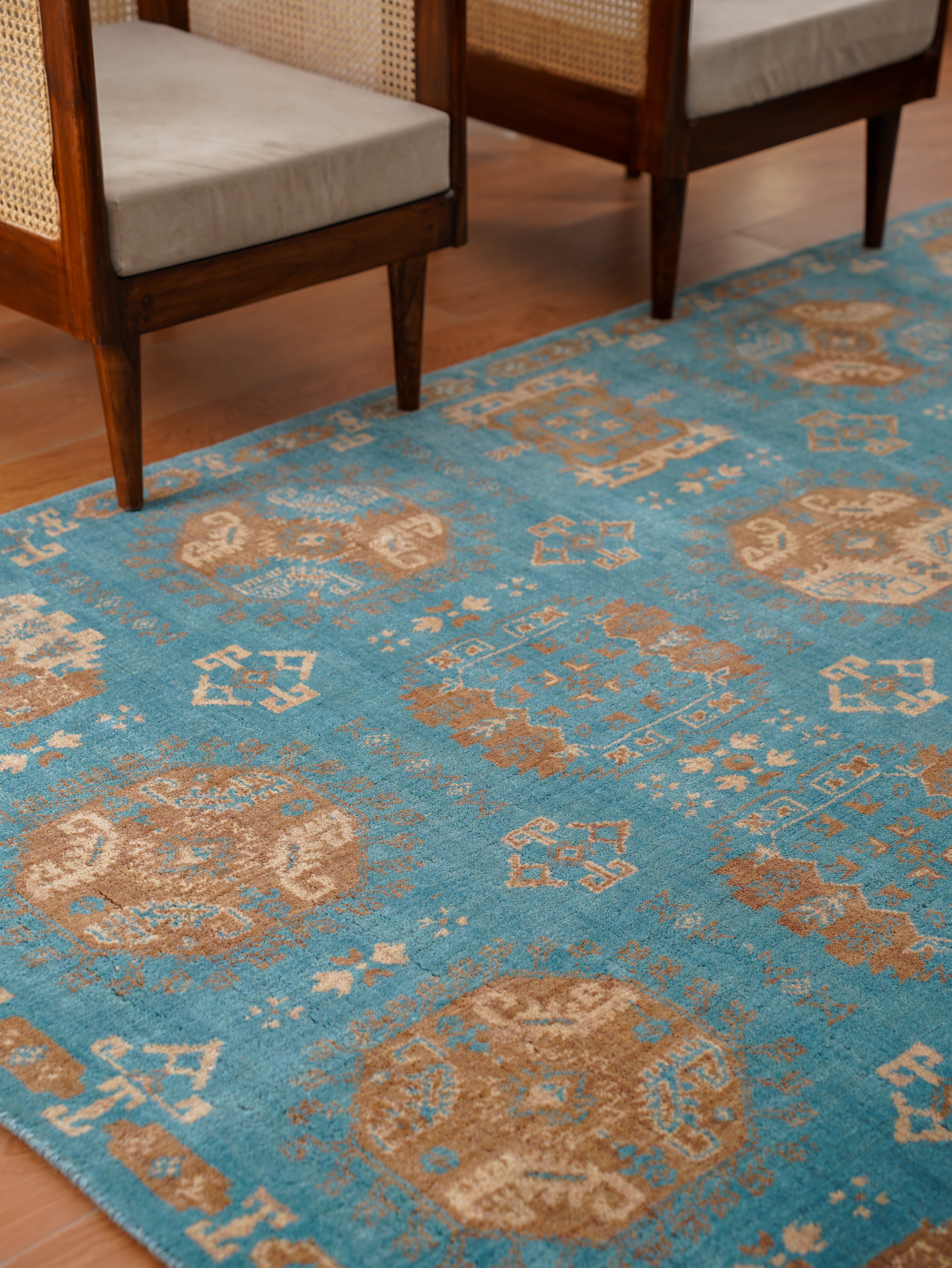 Blue patterned rug with wooden chairs in the background