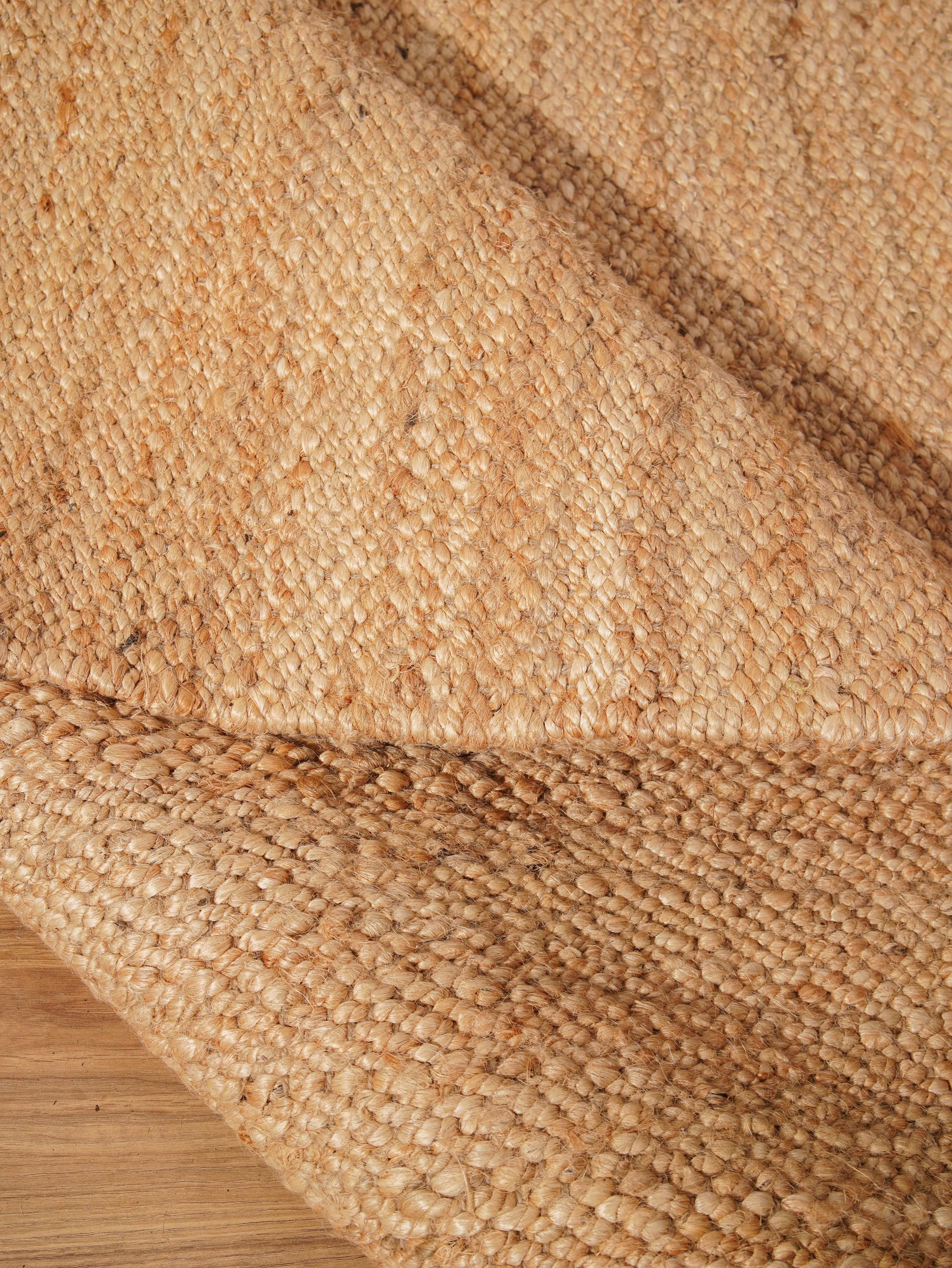 Natural jute flatweave rug rolled and folded for display
