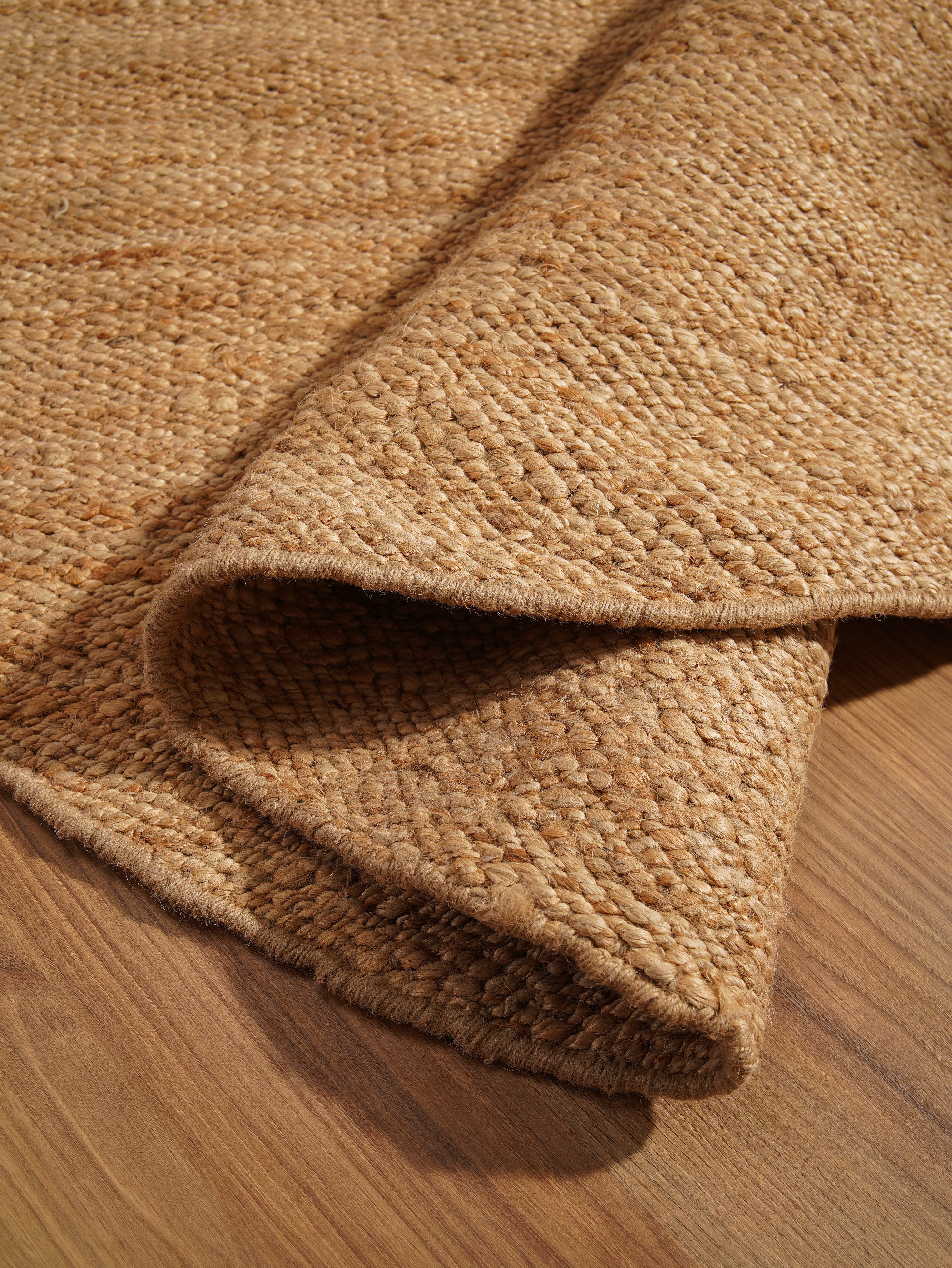 Natural jute flatweave rug rolled and folded for display
